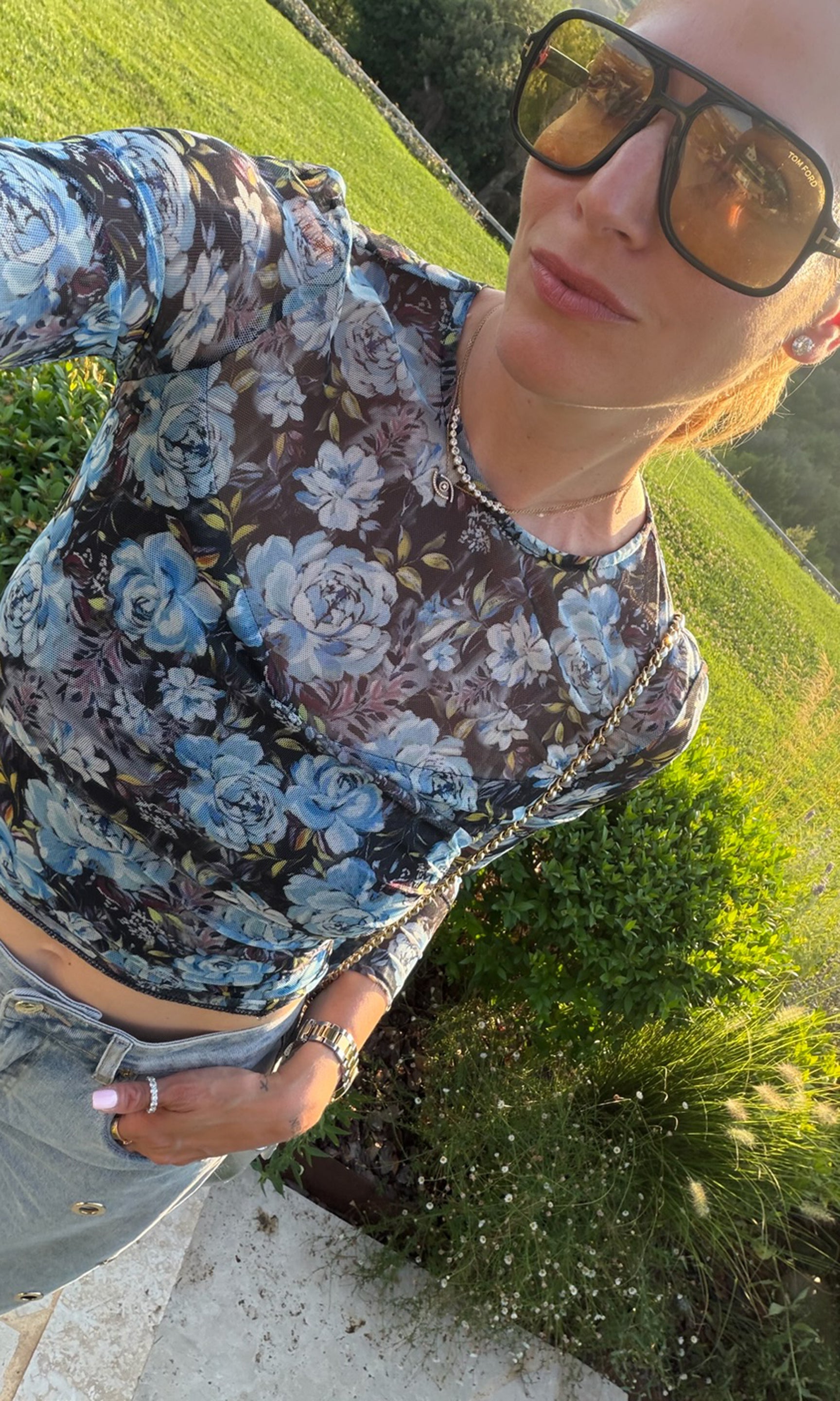 Founder Roni wearing a sheer long-sleeve crop top with a blue, purple, and black floral pattern.