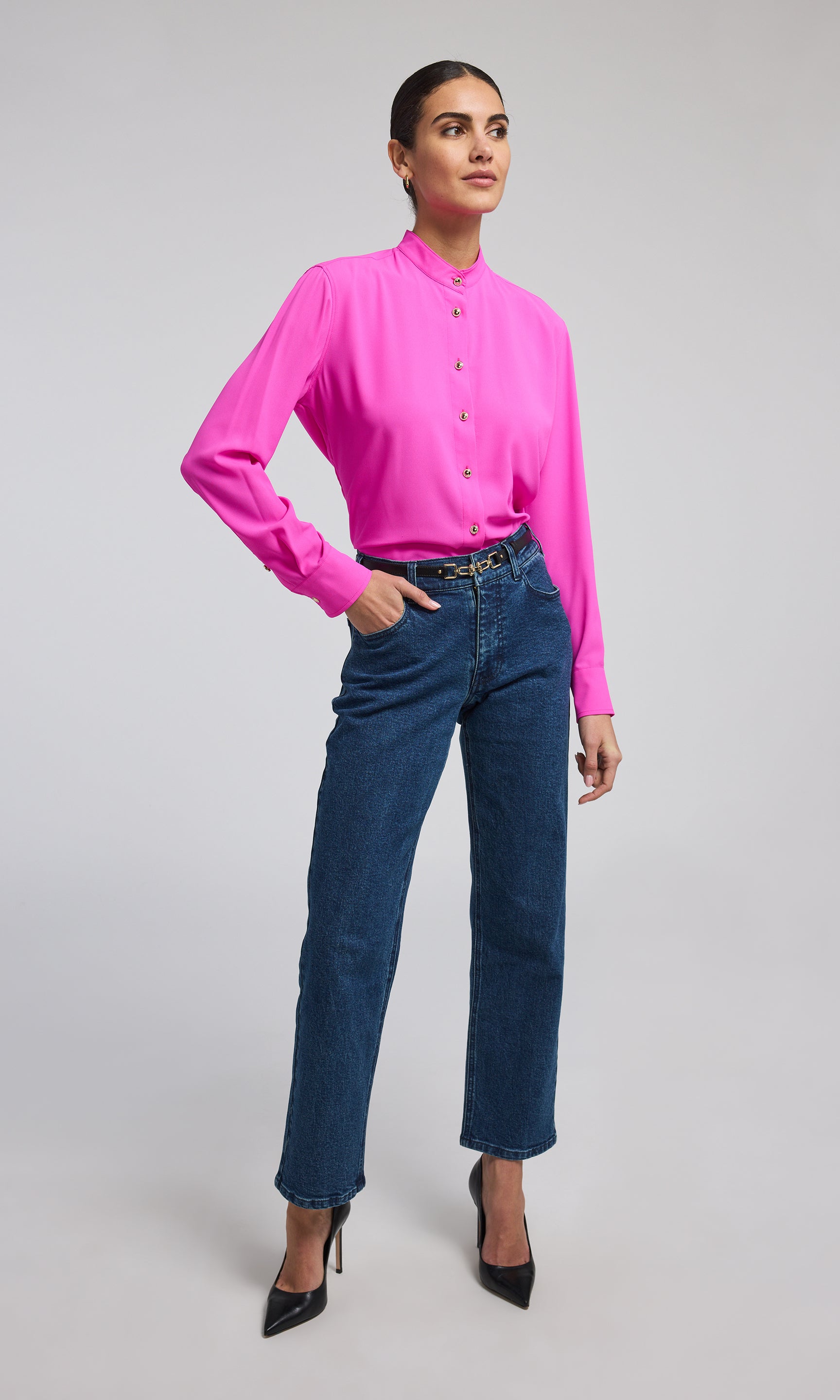 A model showcases a stylish hot pink blouse with gold buttons, highlighting its elegant design and sophisticated color.