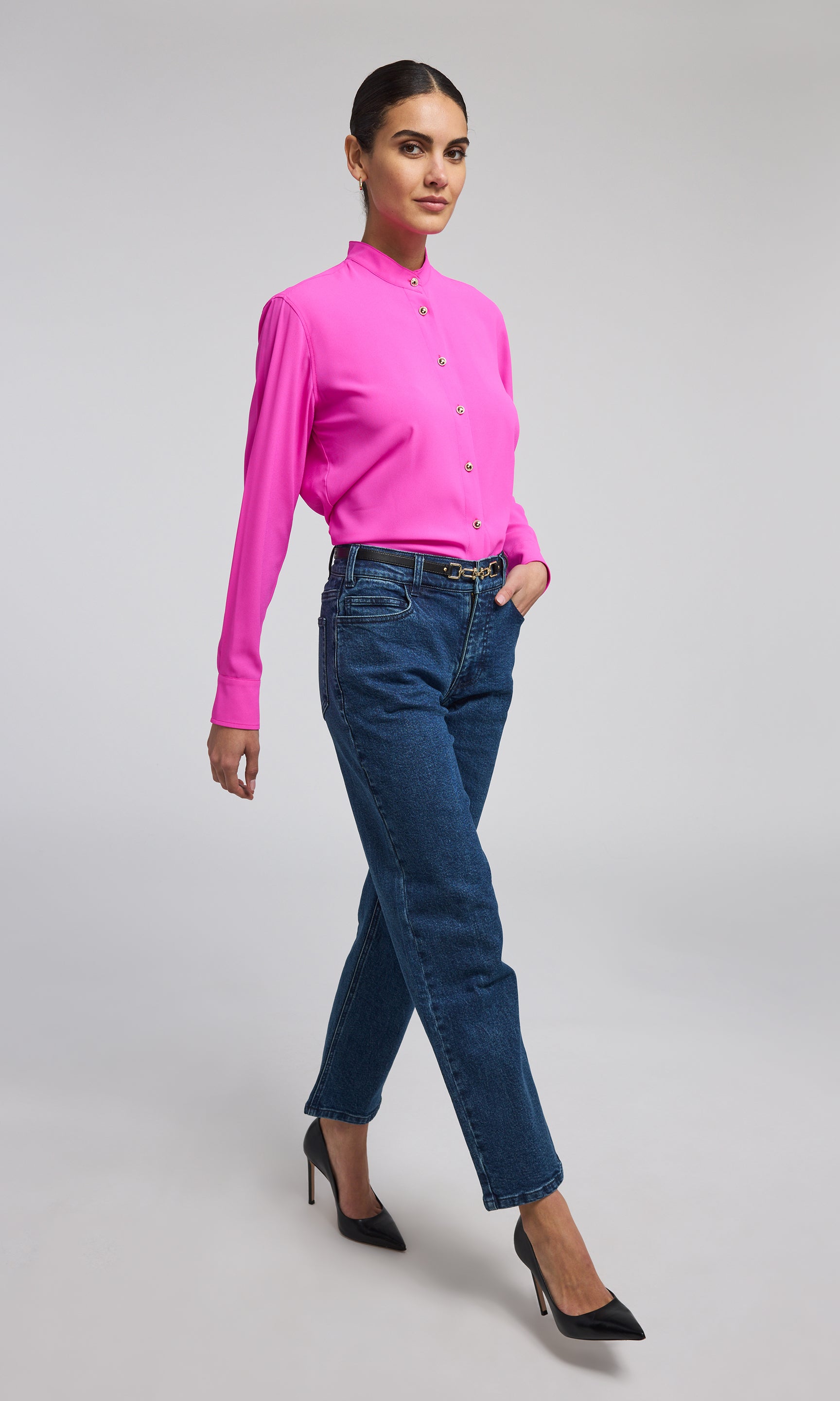 A model showcases a stylish hot pink blouse with gold buttons, highlighting its elegant design and sophisticated color.