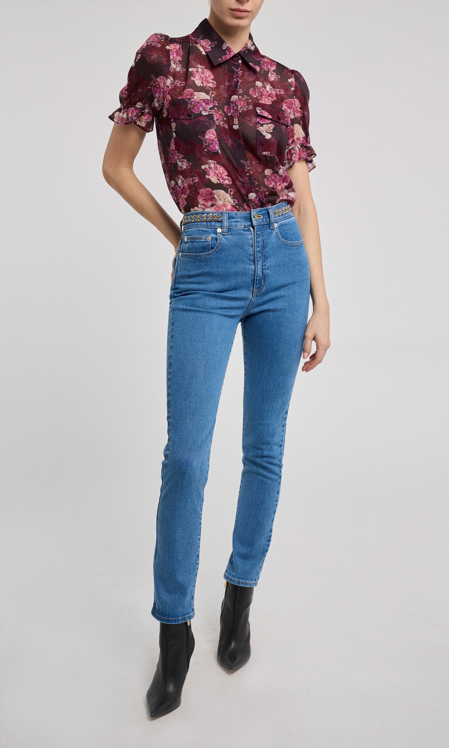 Person wearing a floral blouse and blue jeans on a white background