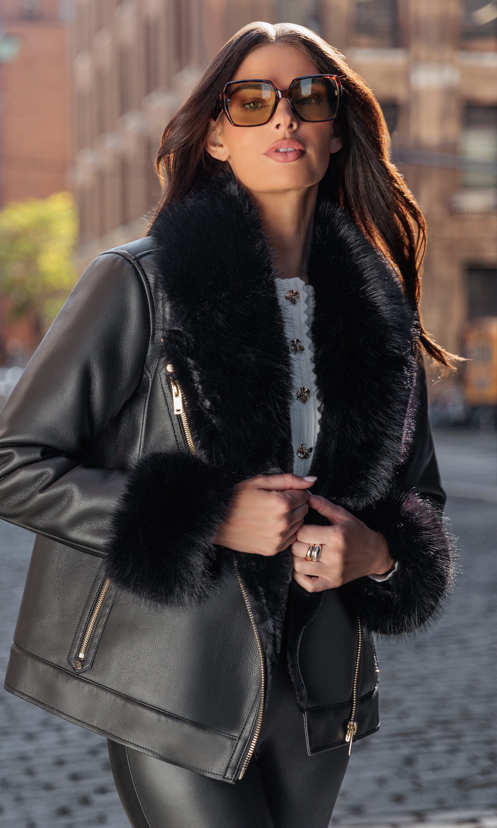 Woman wearing a black leather jacket with fur trim in an urban setting