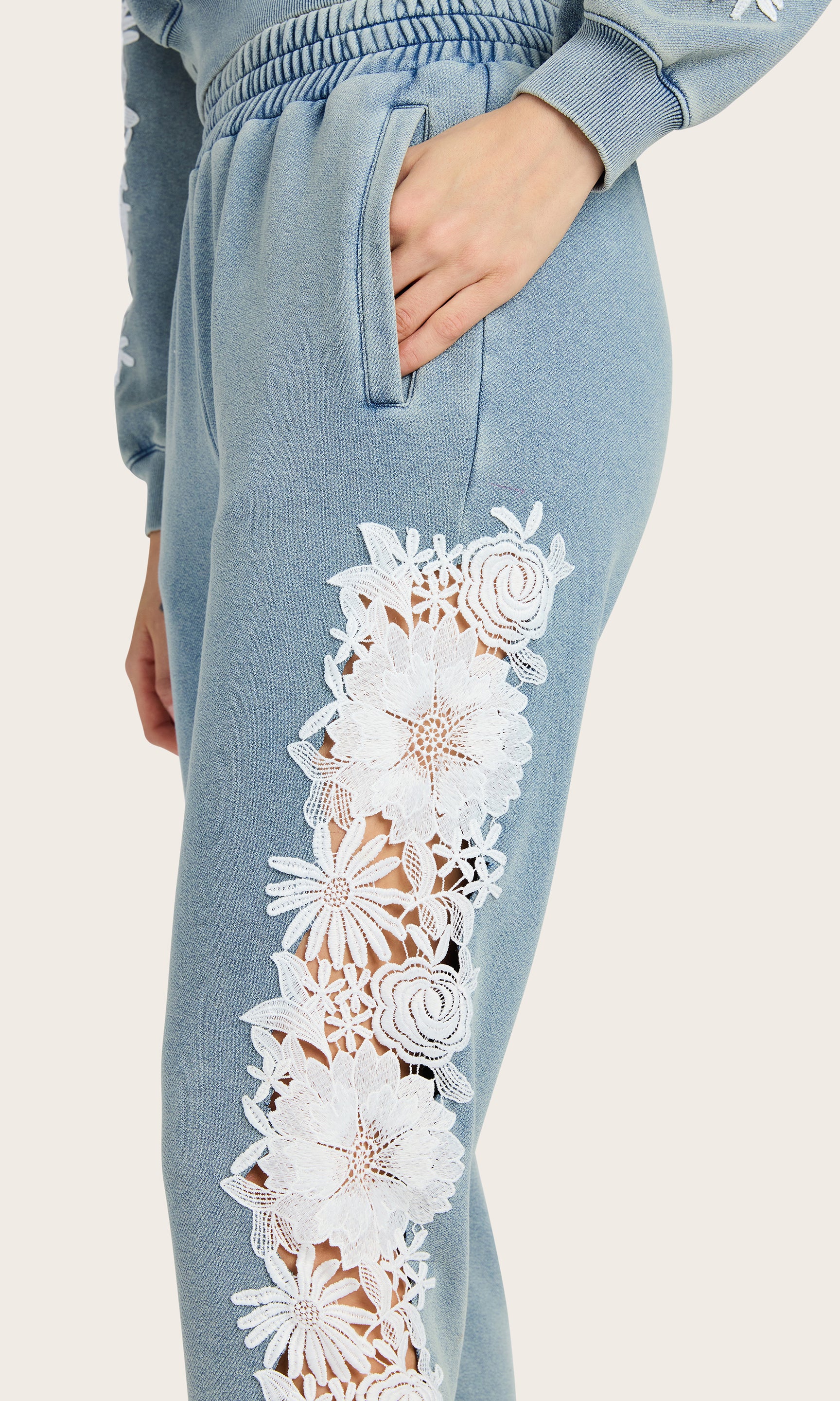 detailed side view of model wearing the Winnie washed denim joggers with white lace details on the side, paired with a matching sweatshirt