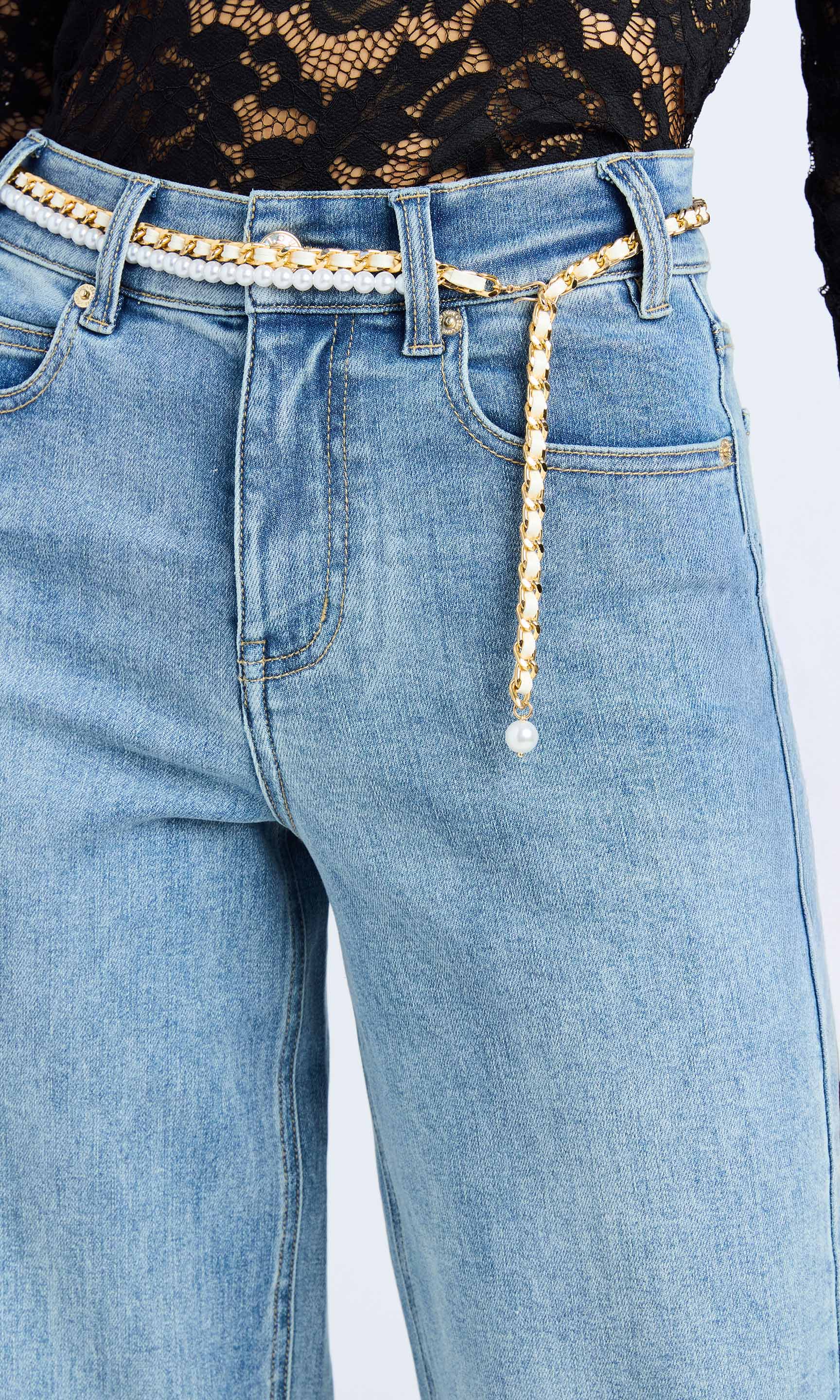 Close-up of a woman wearing a blue sweater and denim jeans, highlighted by a pearl belt.