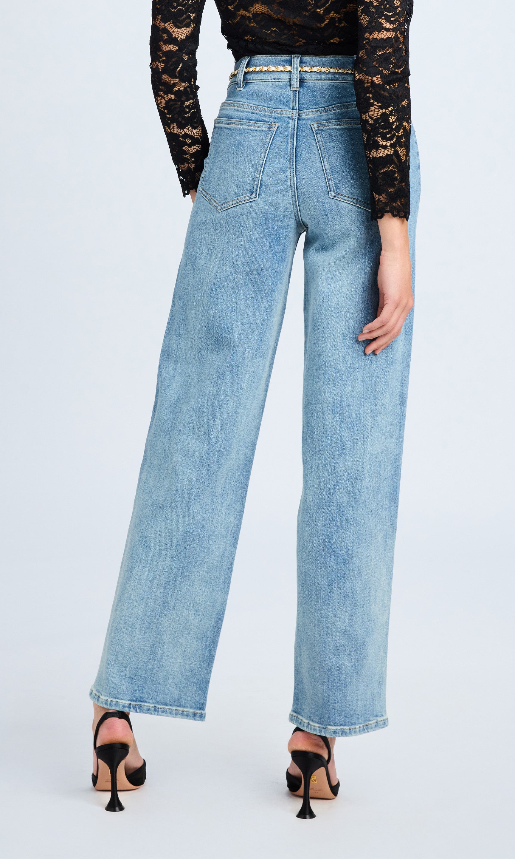 Rear view of a woman in high-rise jeans, standing tall and confident, emphasizing her stylish look.