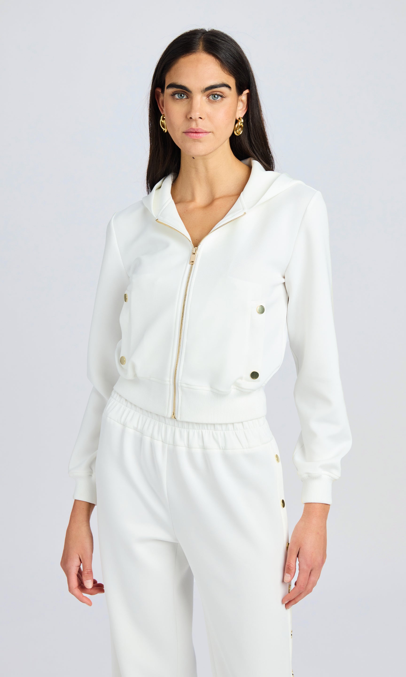 model stands wearing a white scuba fabric zip up hoodie with matching pants.