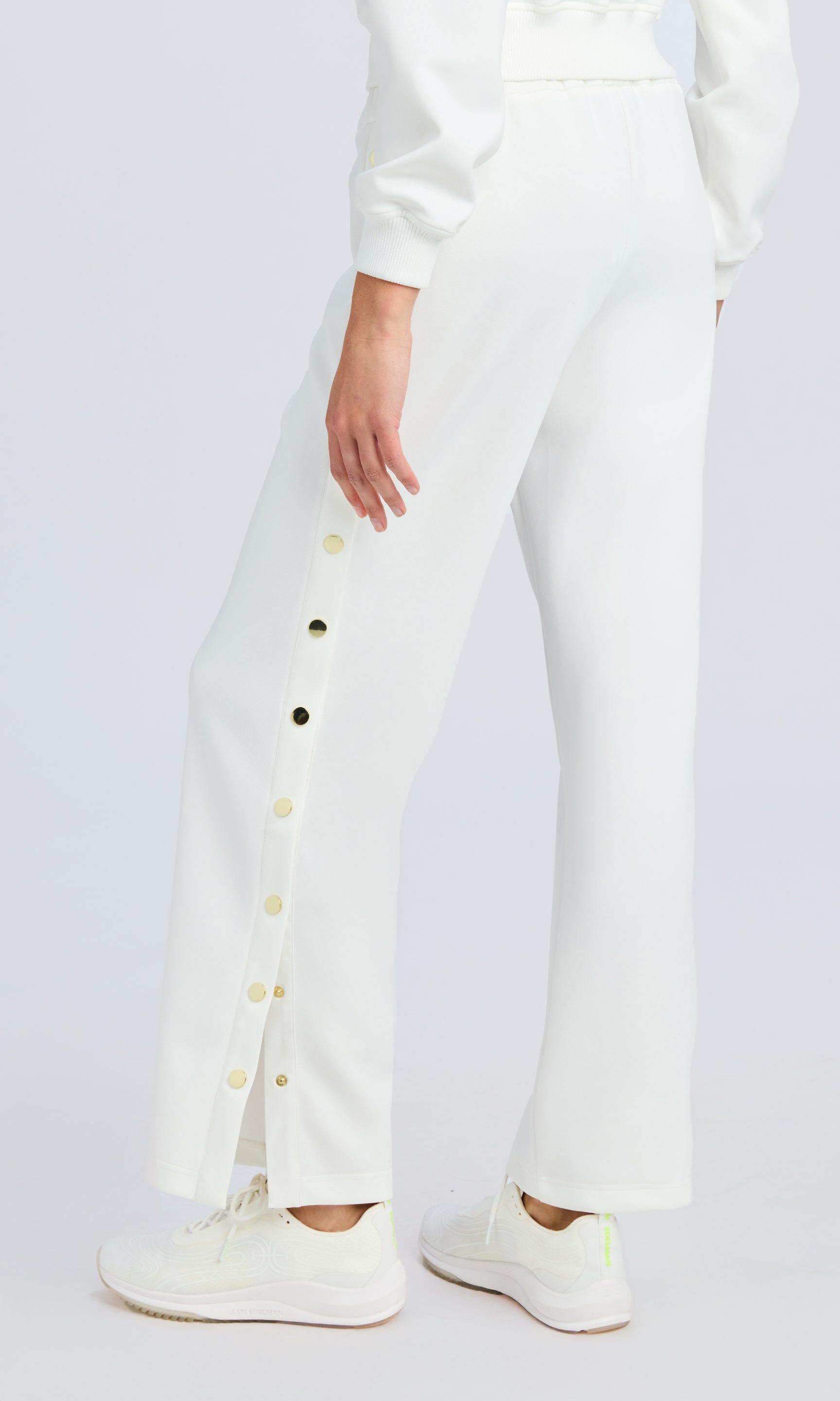 back shot of white scuba sweatpants with gold snaps down the side.