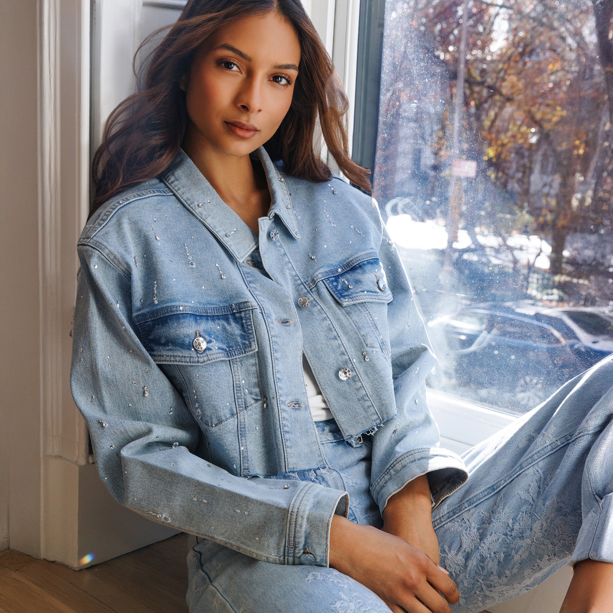 Woman wearing a denim outfit sitting by a window