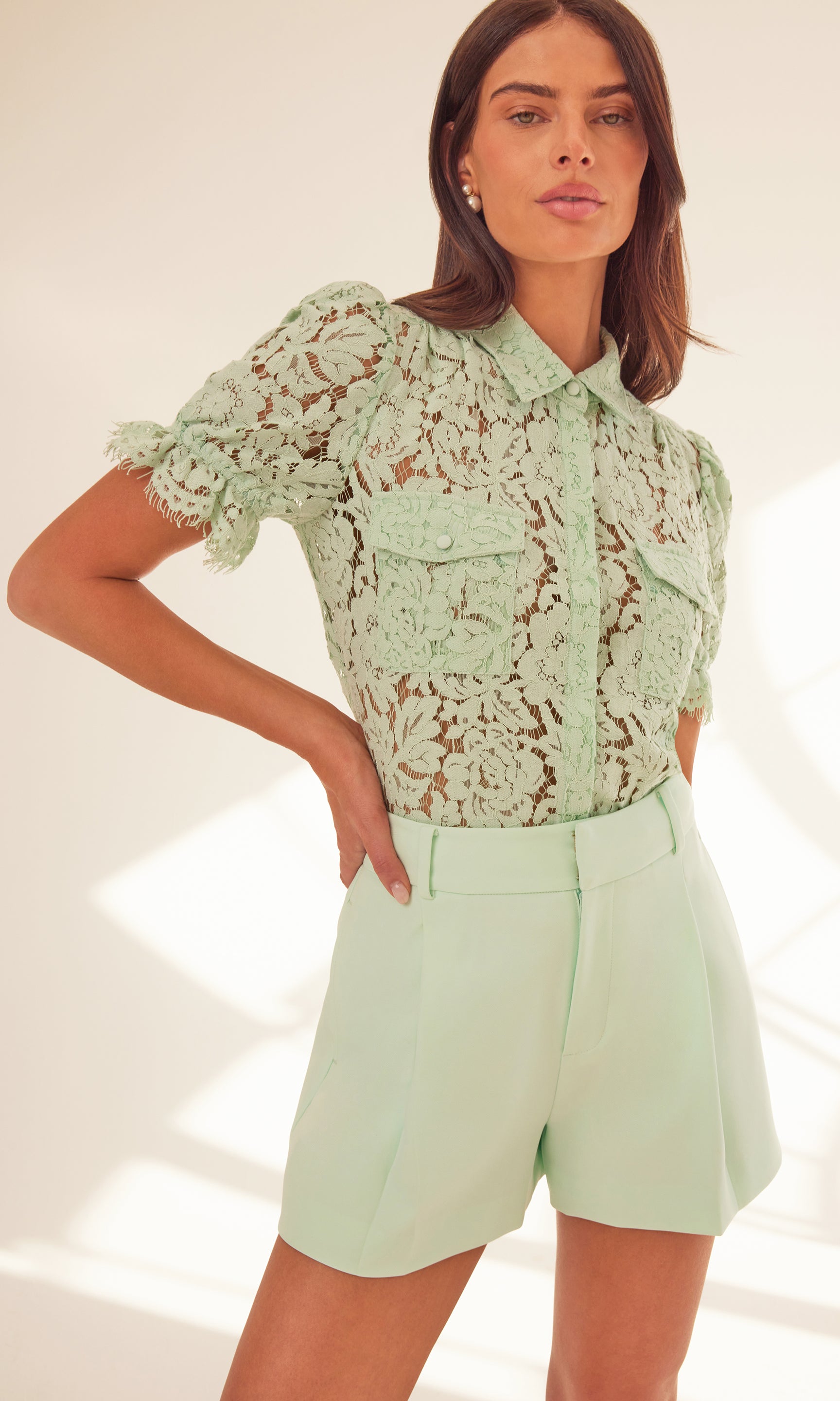 image of model standing with her hand on her hip, wearing a seafoam lace top paired with the Sena crepe shorts in seafoam
