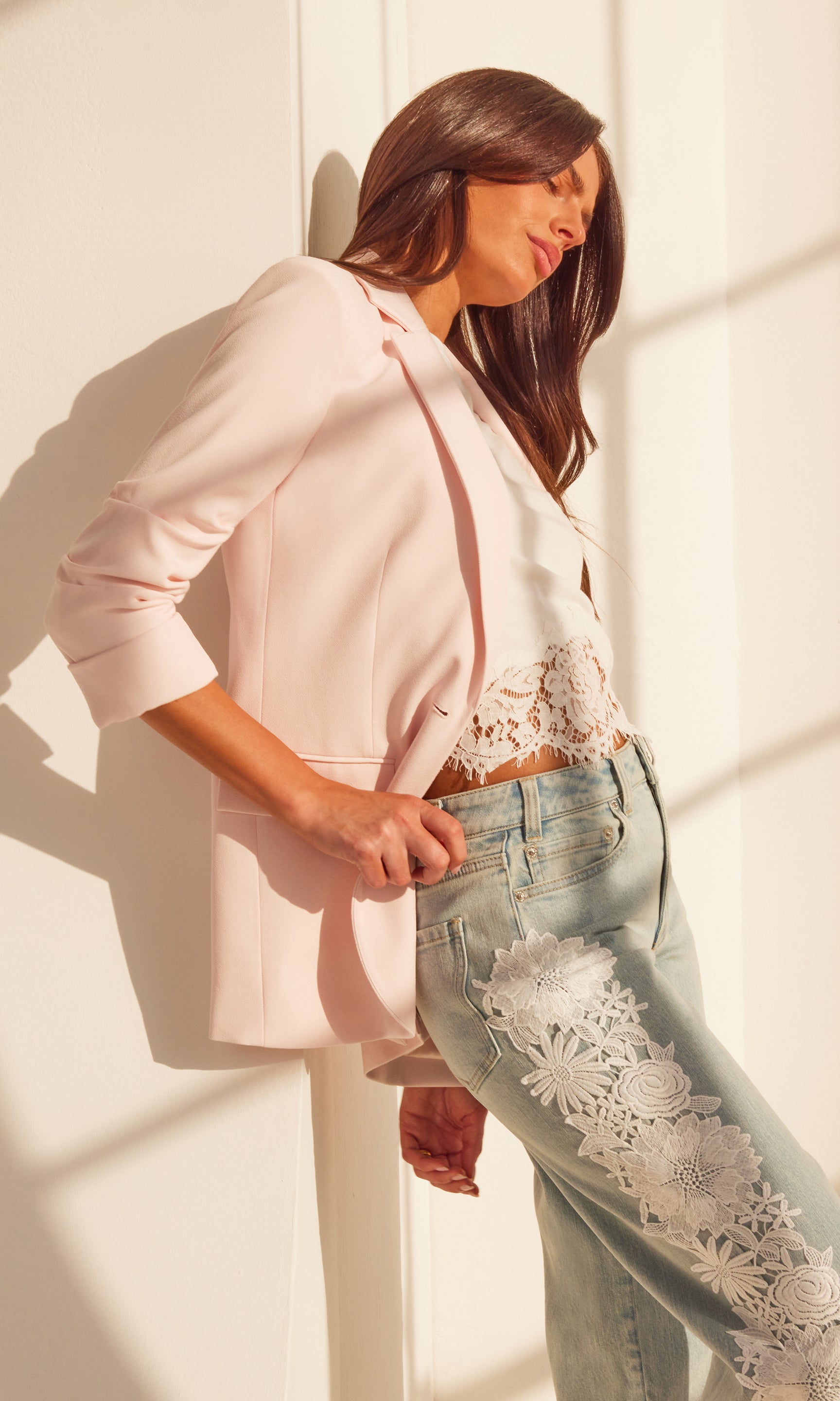 Side view of the model wearing the Drea Light Weight Crepe Blazer in light pink, styled casually over a pair of printed jeans.