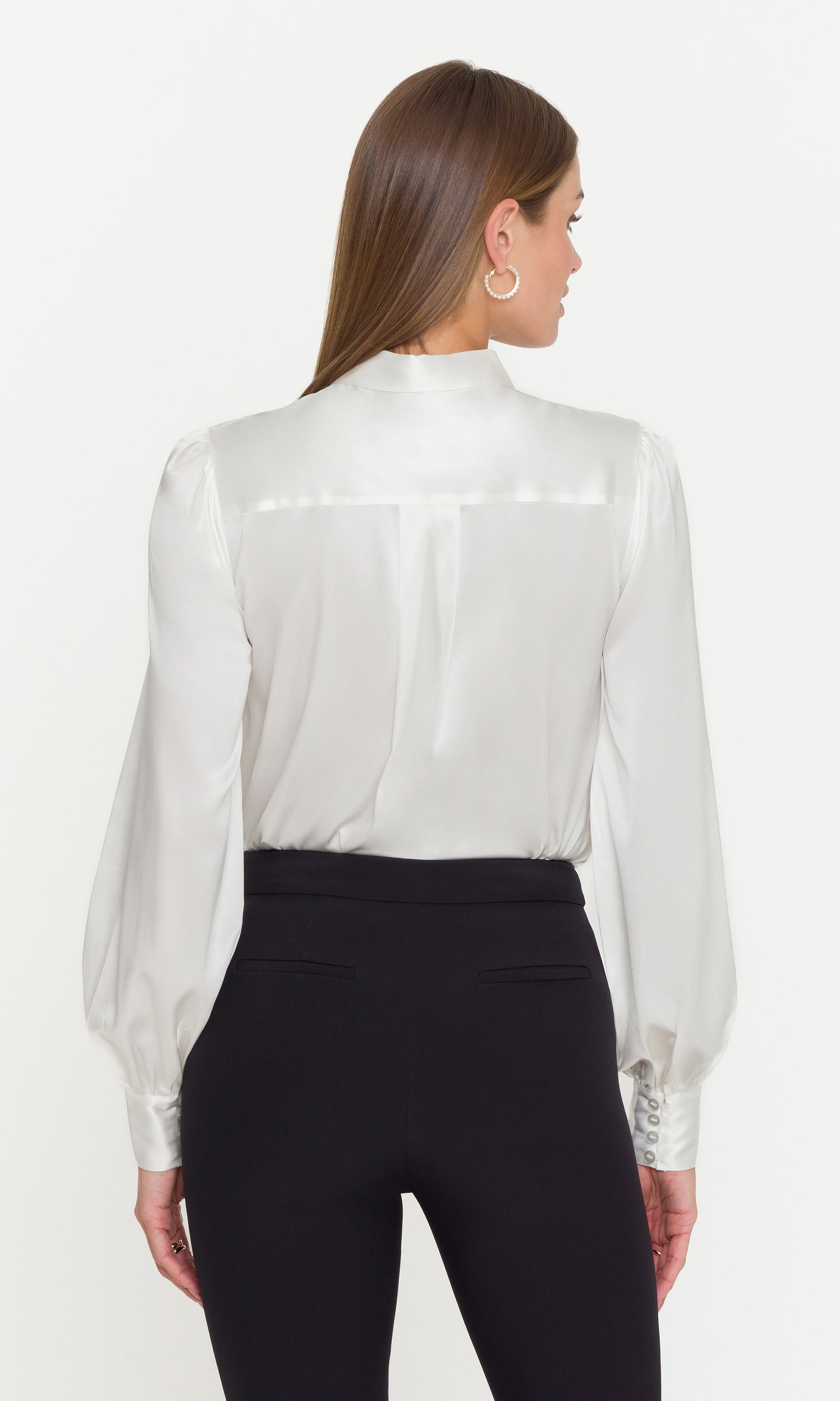 Back view of model wearing a white blouse with sheer sleeves on a white background