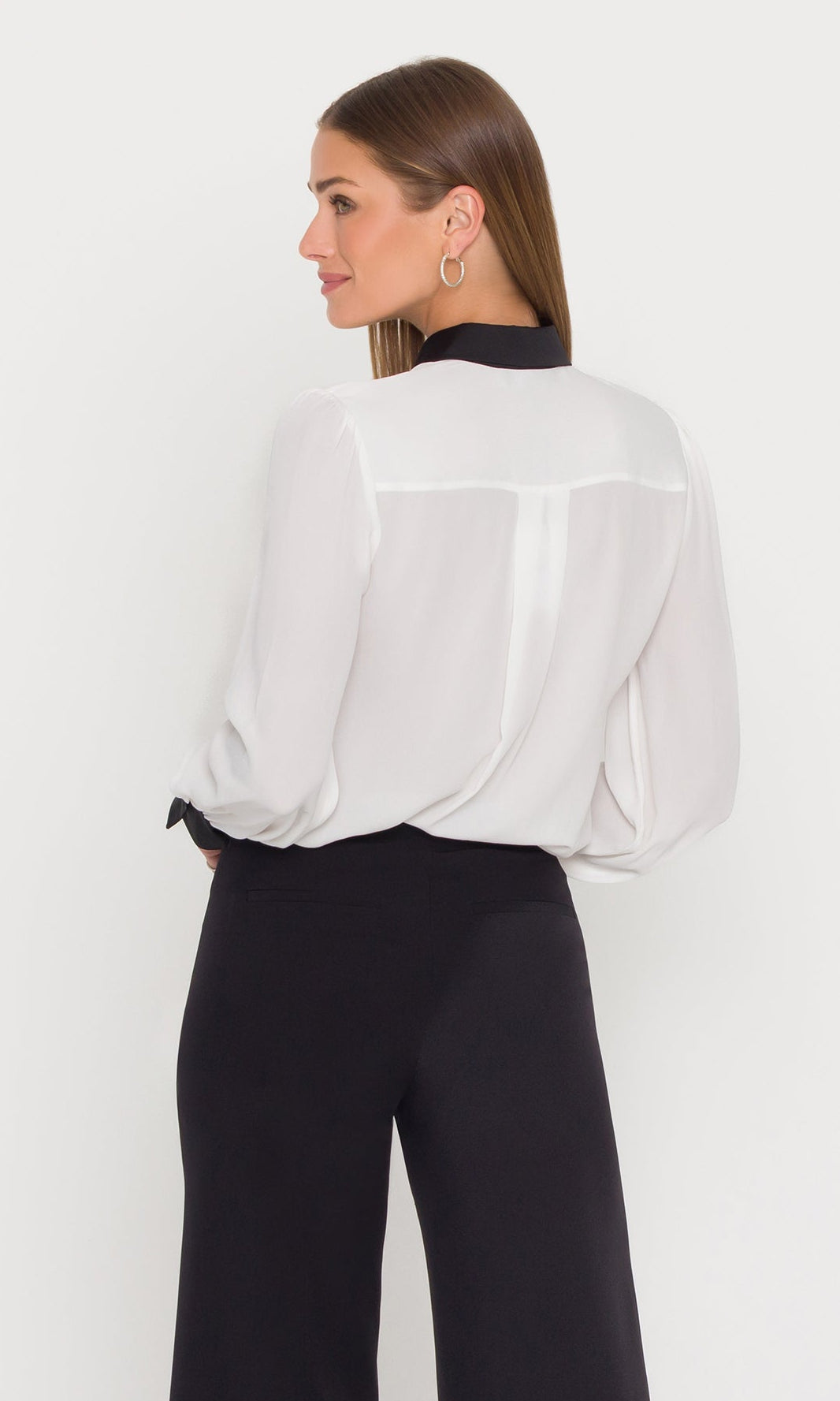 Woman wearing a white blouse and black pants on a white background
