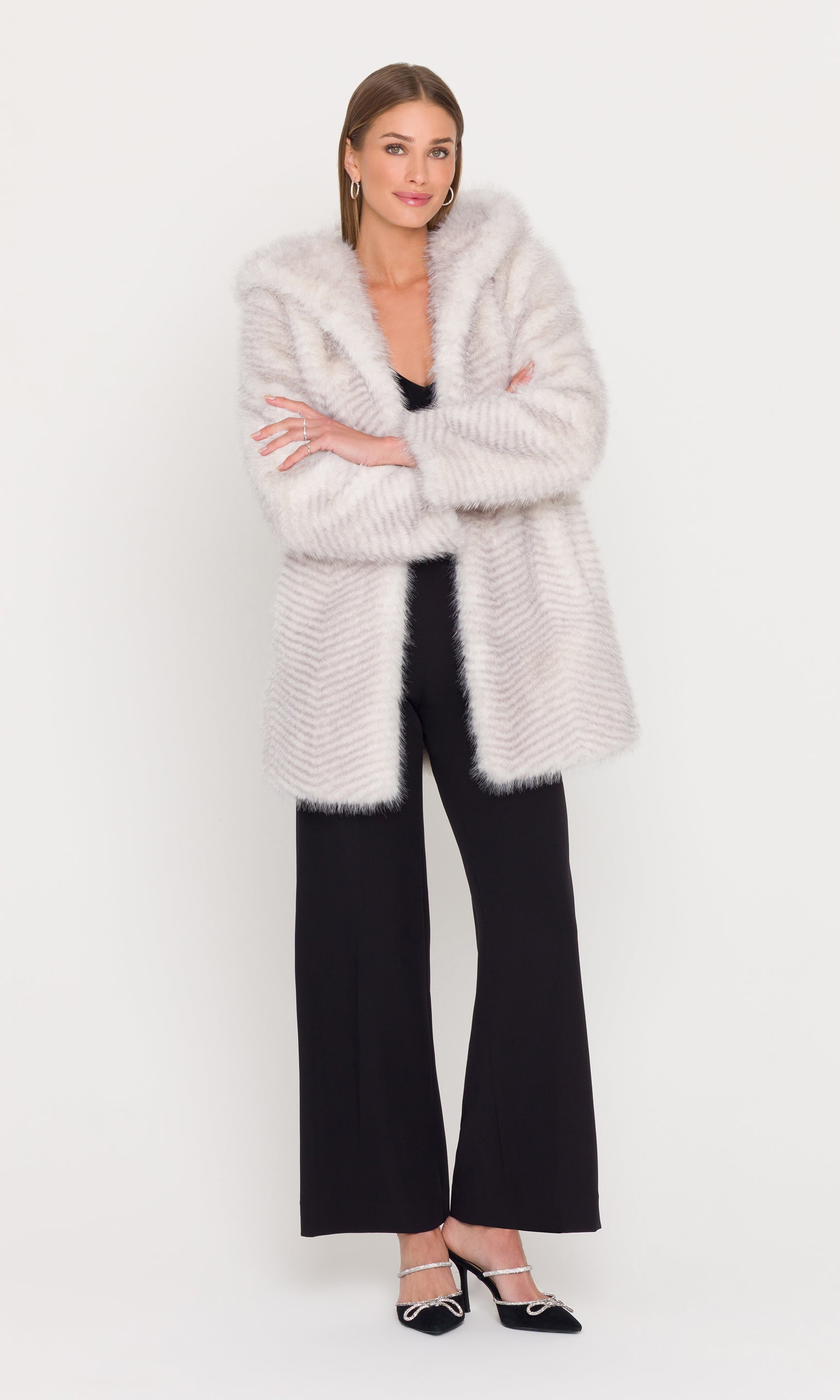 Woman wearing a long cream faux fur coat on a white background
