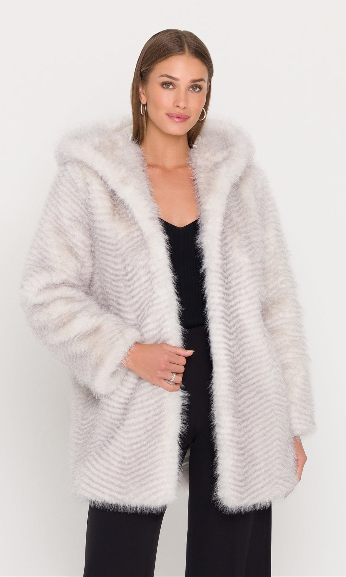 Woman wearing a cream fur coat over a black outfit on a white background