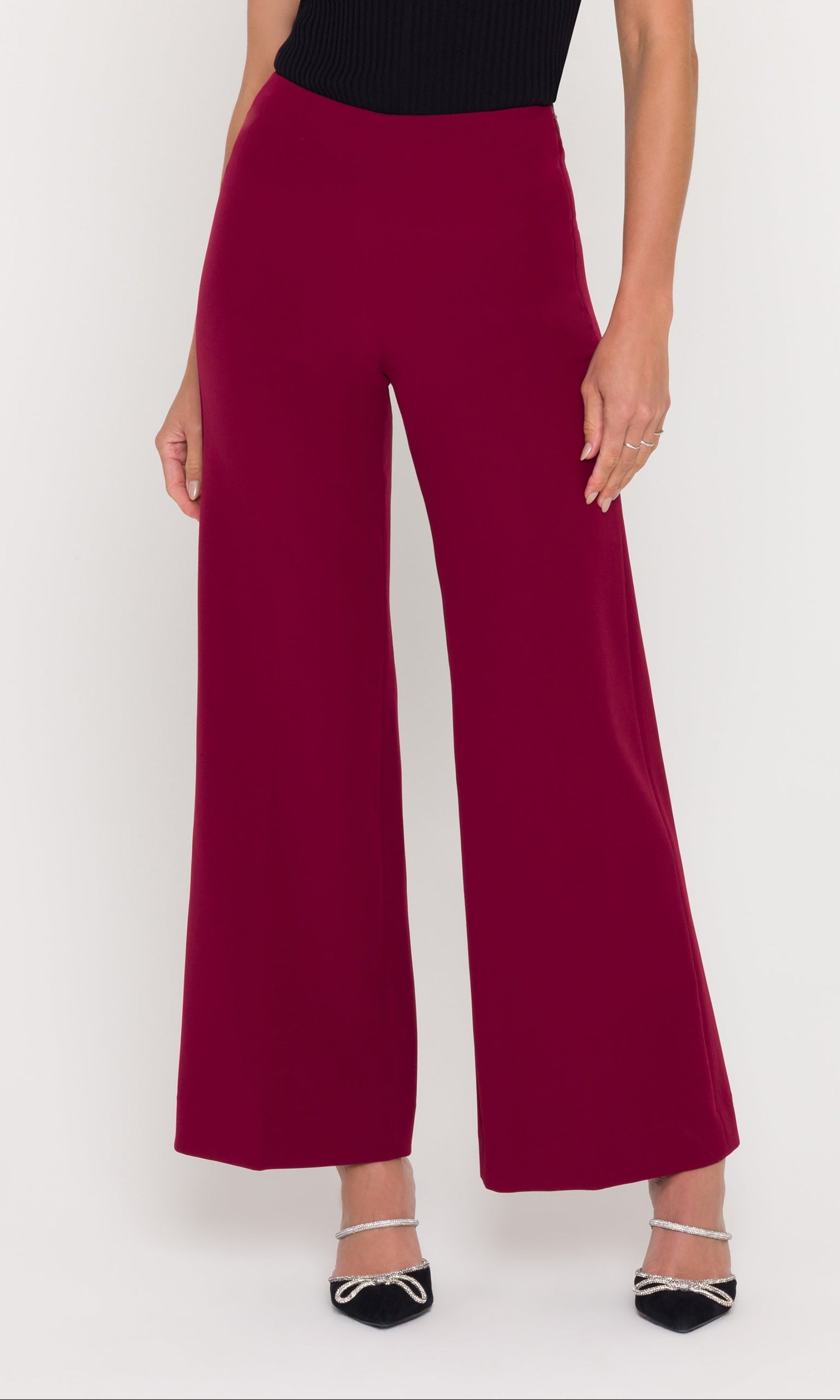 Person wearing crimson wide-leg pants and a black top on a white background