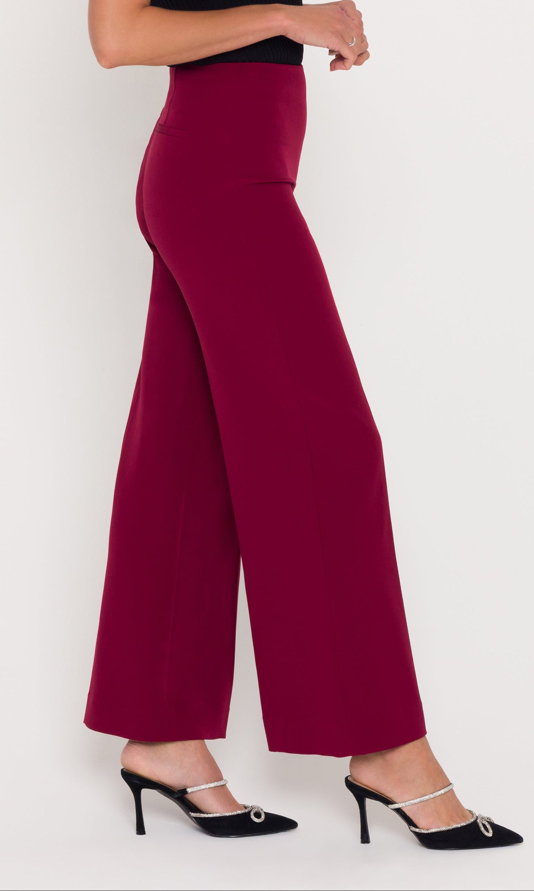 Person wearing crimson wide-leg pants and black top on a white background
