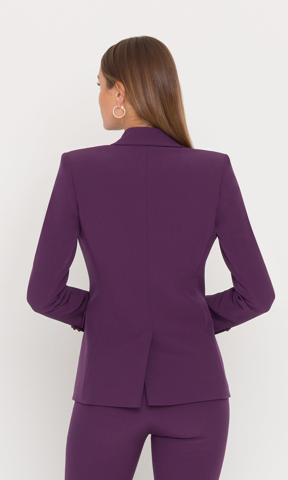 Back view of model wearing eggplant blazer with gold buttons.