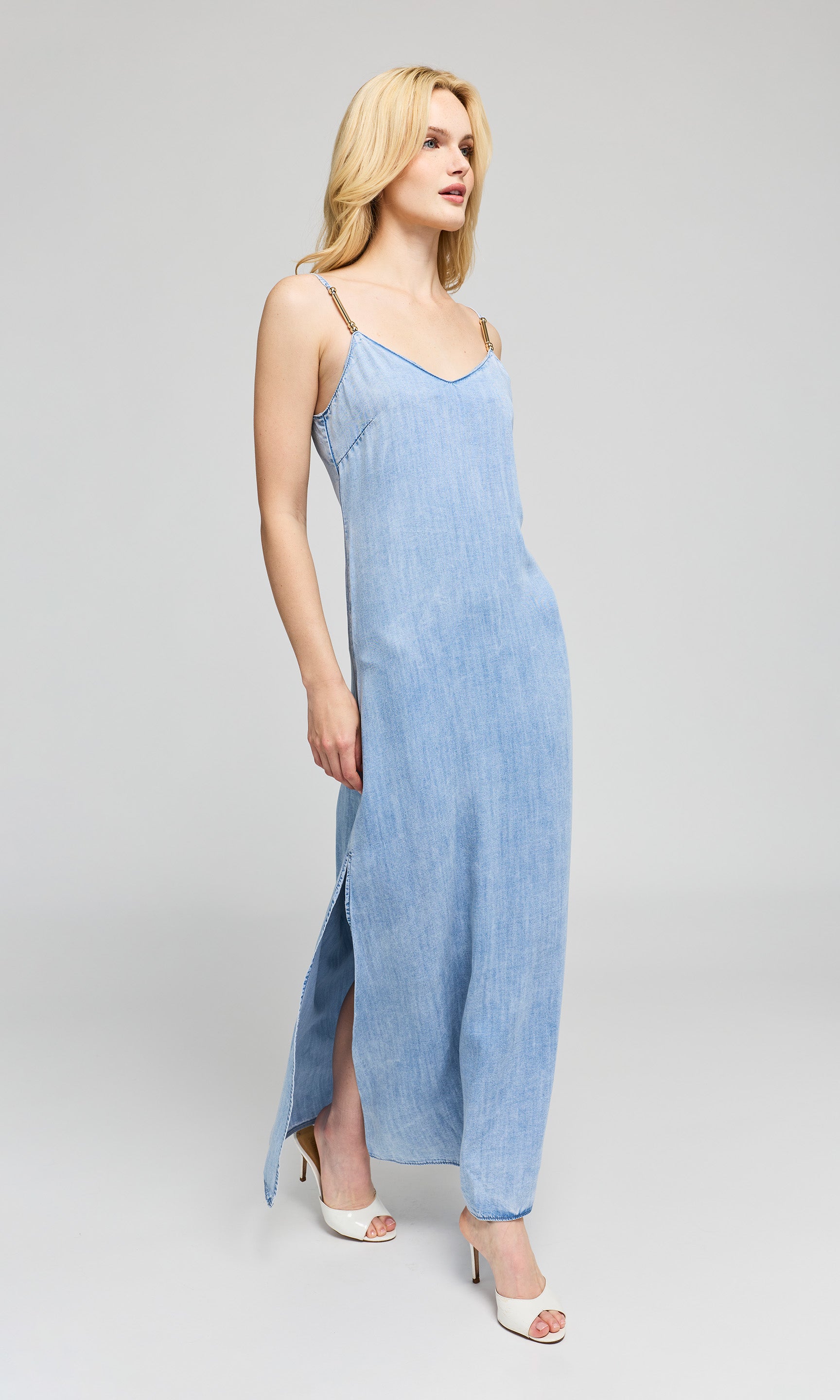 Side view of woman wearing a light blue slip dress on a gray background