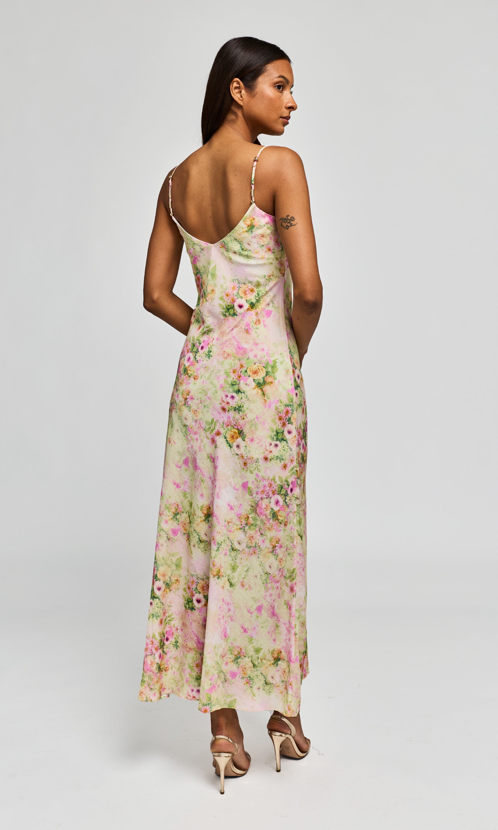 Back view of woman wearing a floral dress on a white background