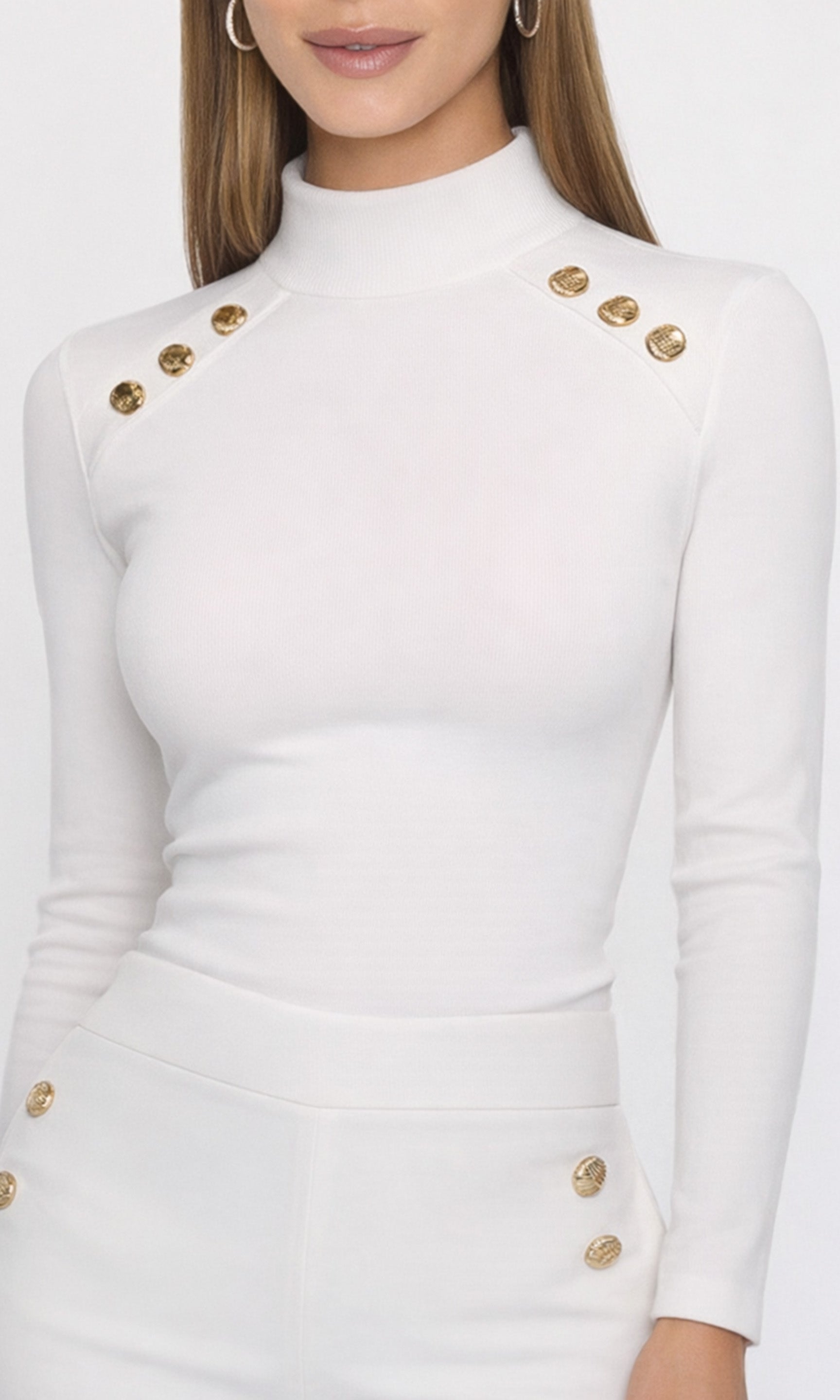 Close-up of white long-sleeve top with gold buttons worn by a person