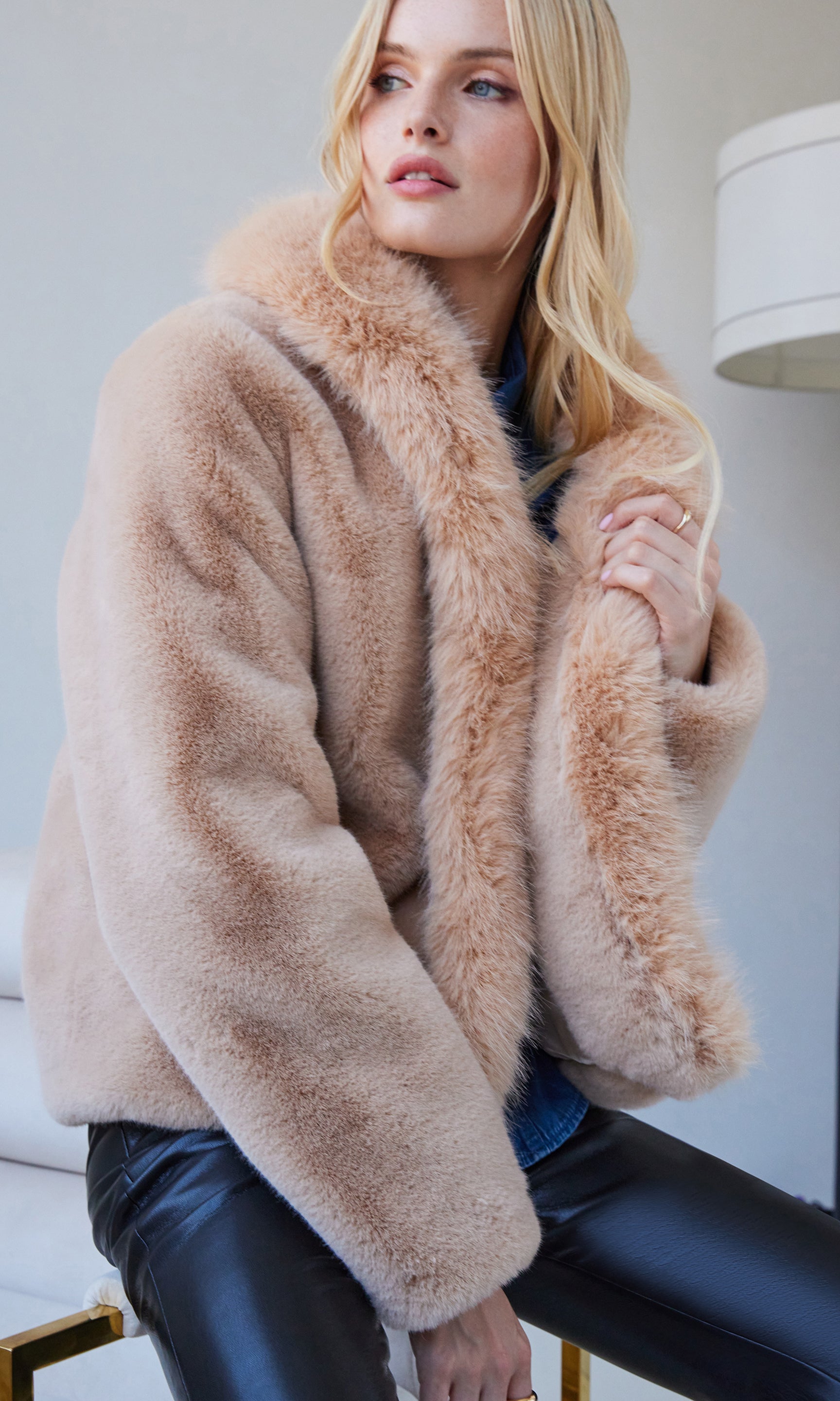 Angled front view showcasing the plush texture of the beige faux fur jacket paired with sleek black leather pants.