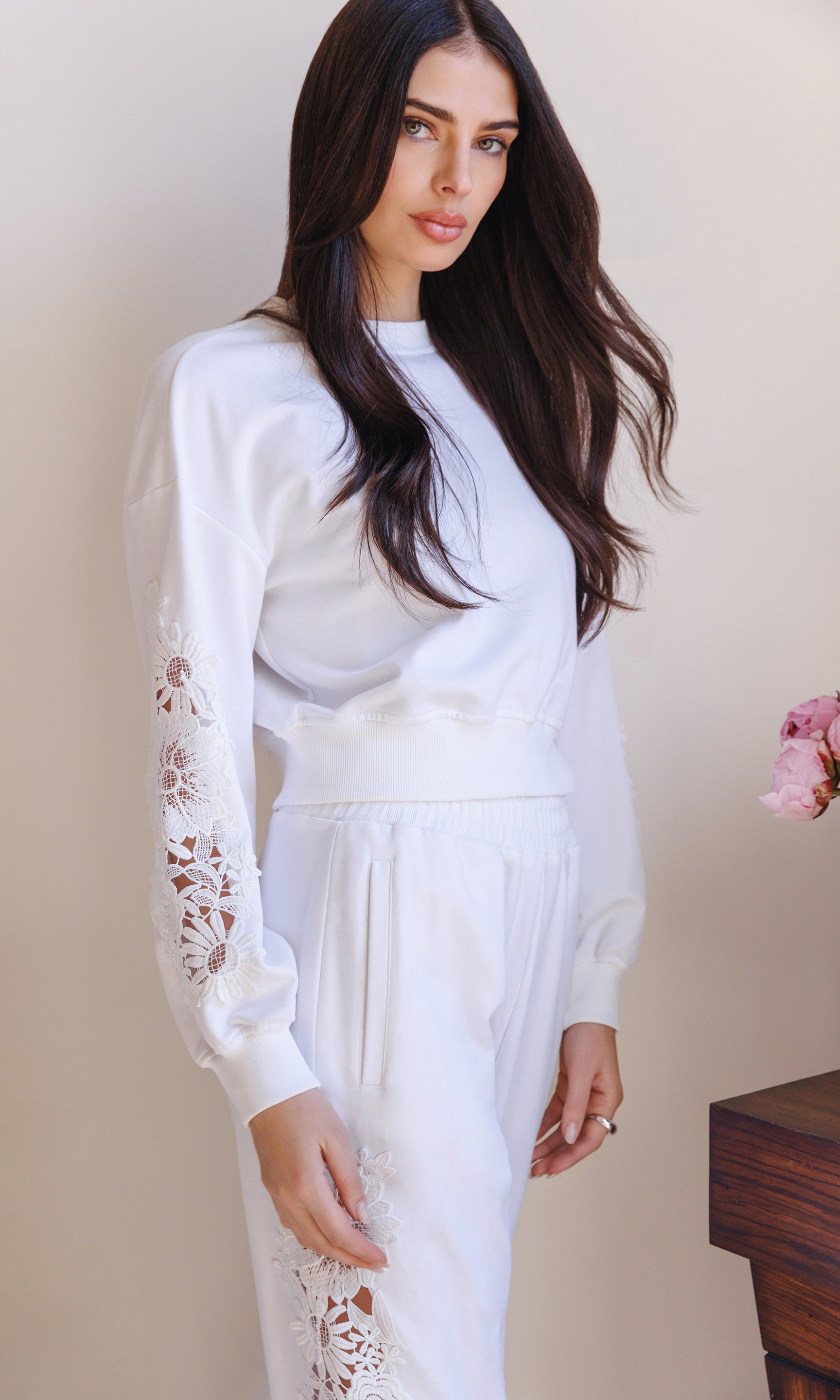In a three-quarter front view, the model wears the Arabella Lace Combo Sweatshirt in white, emphasizing the lace sleeve panels and clean crew neckline.