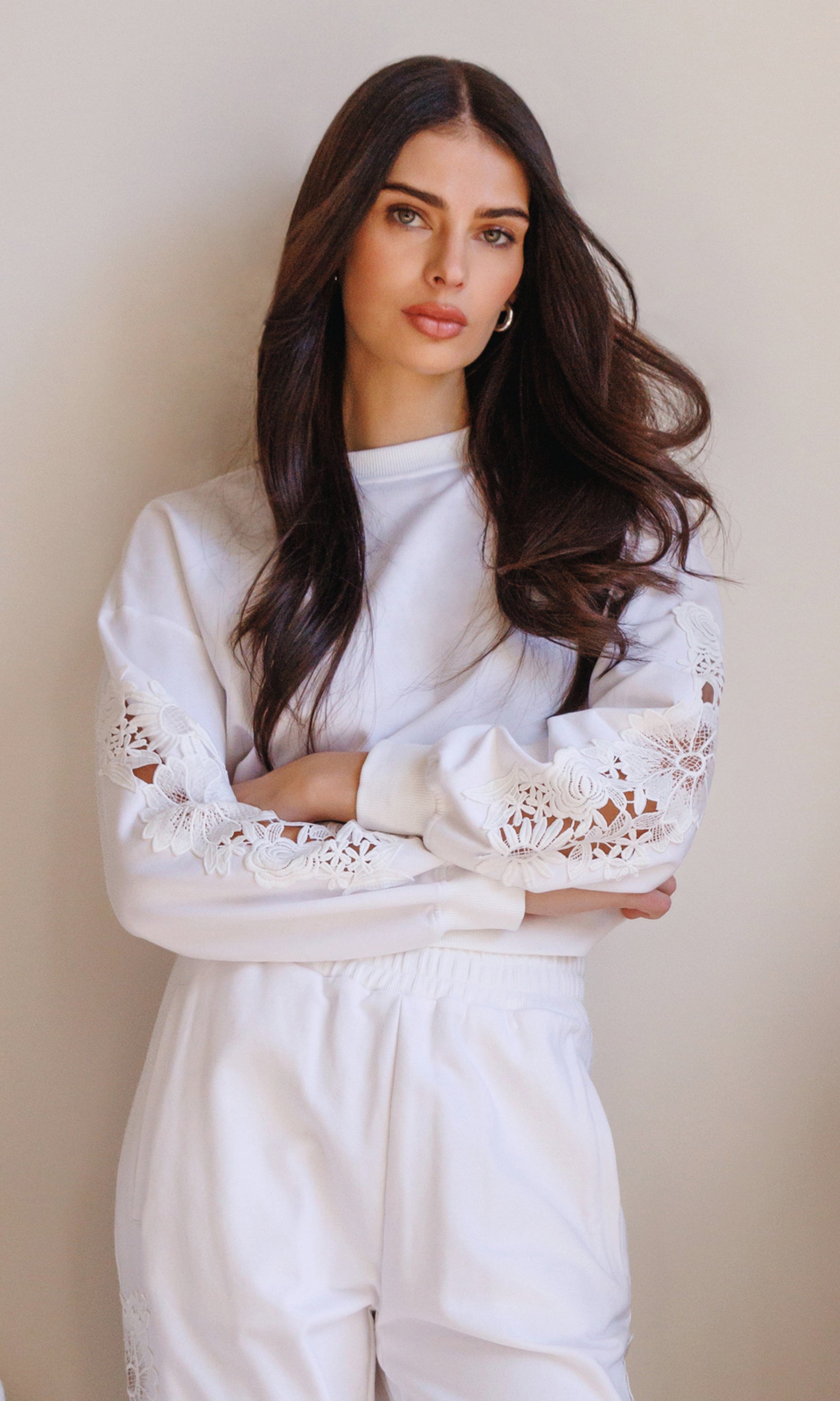 In a three-quarter front view, the model styles the Arabella Lace Combo Sweatshirt in white, showcasing the lace cutout sleeves and soft, elevated loungewear look.