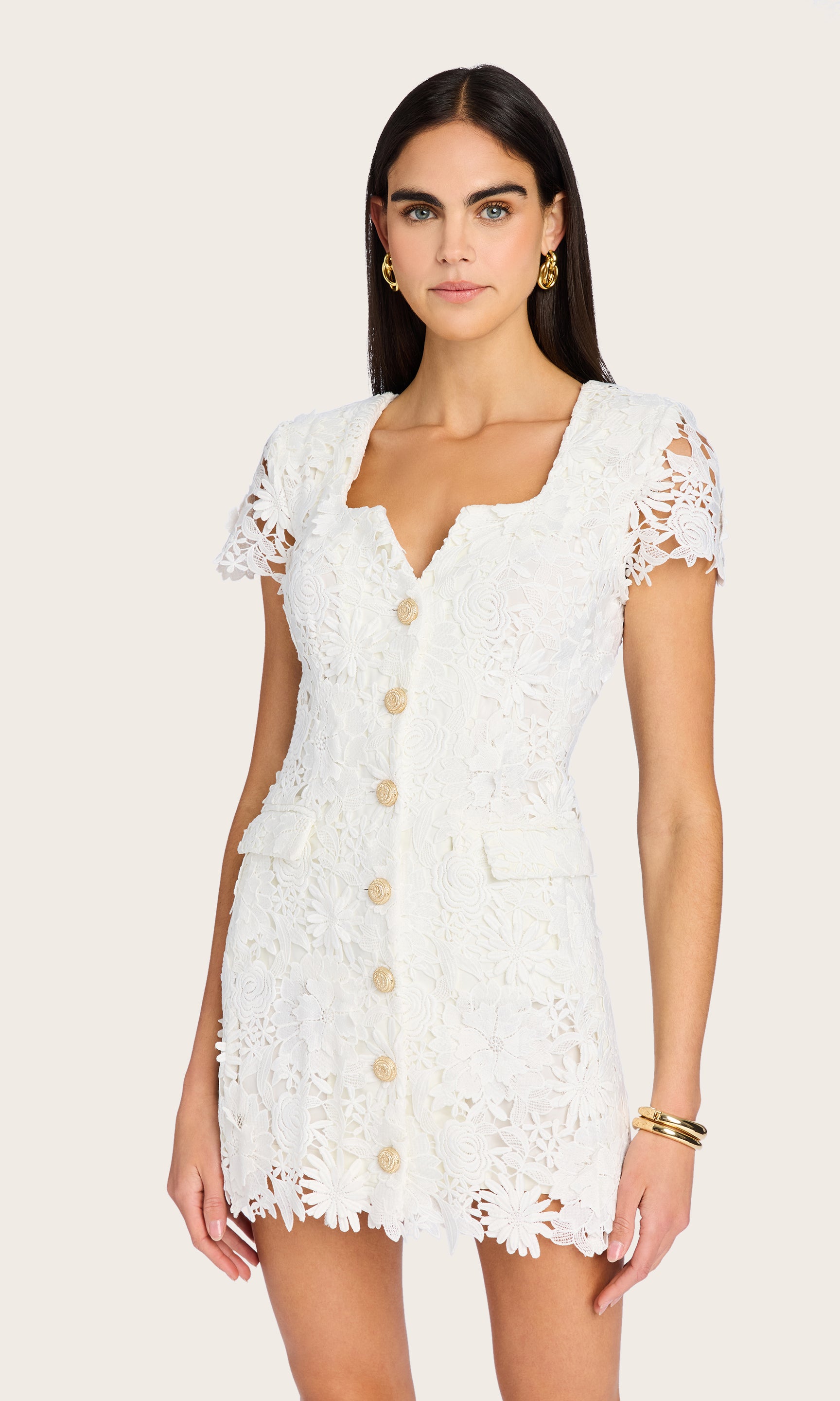 The model wears the white Brunella 3D Lace Dress in a front view, showcasing its button-down front and intricate floral lace detailing.