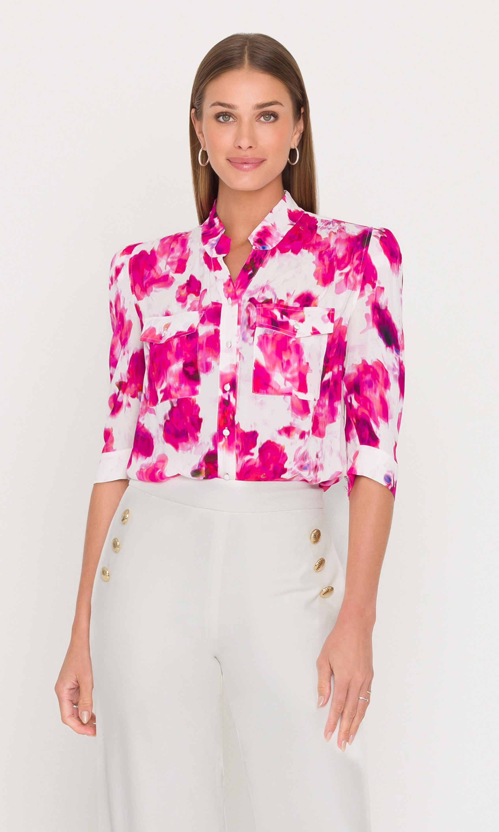 Woman wearing a pink and white floral blouse with a plain background