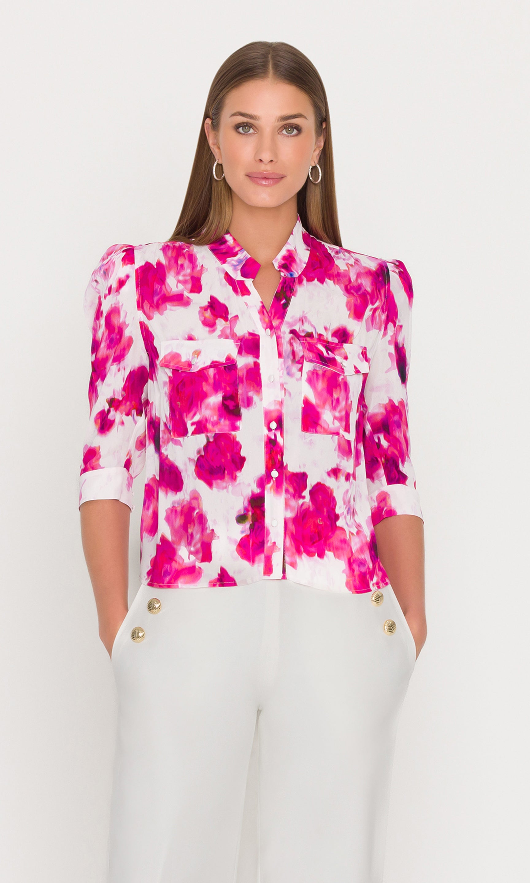 Woman wearing a pink floral blouse with white pants on a white background