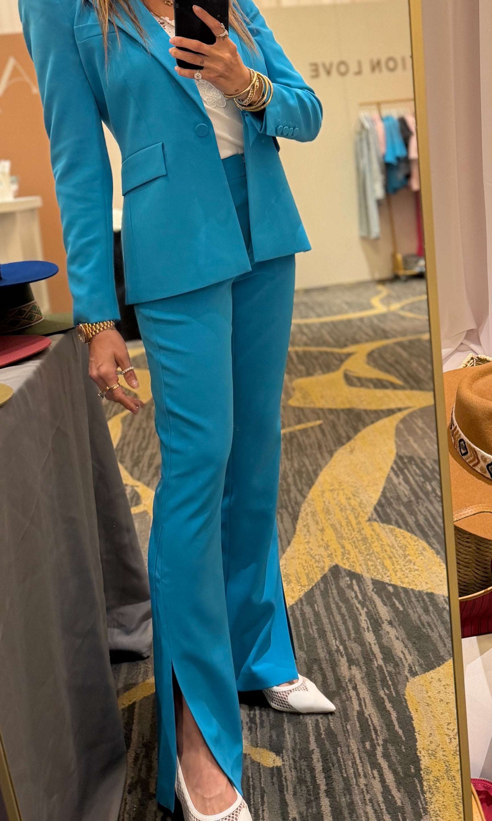 Founder Roni wearing a blue suit standing in front of a mirror in a store.