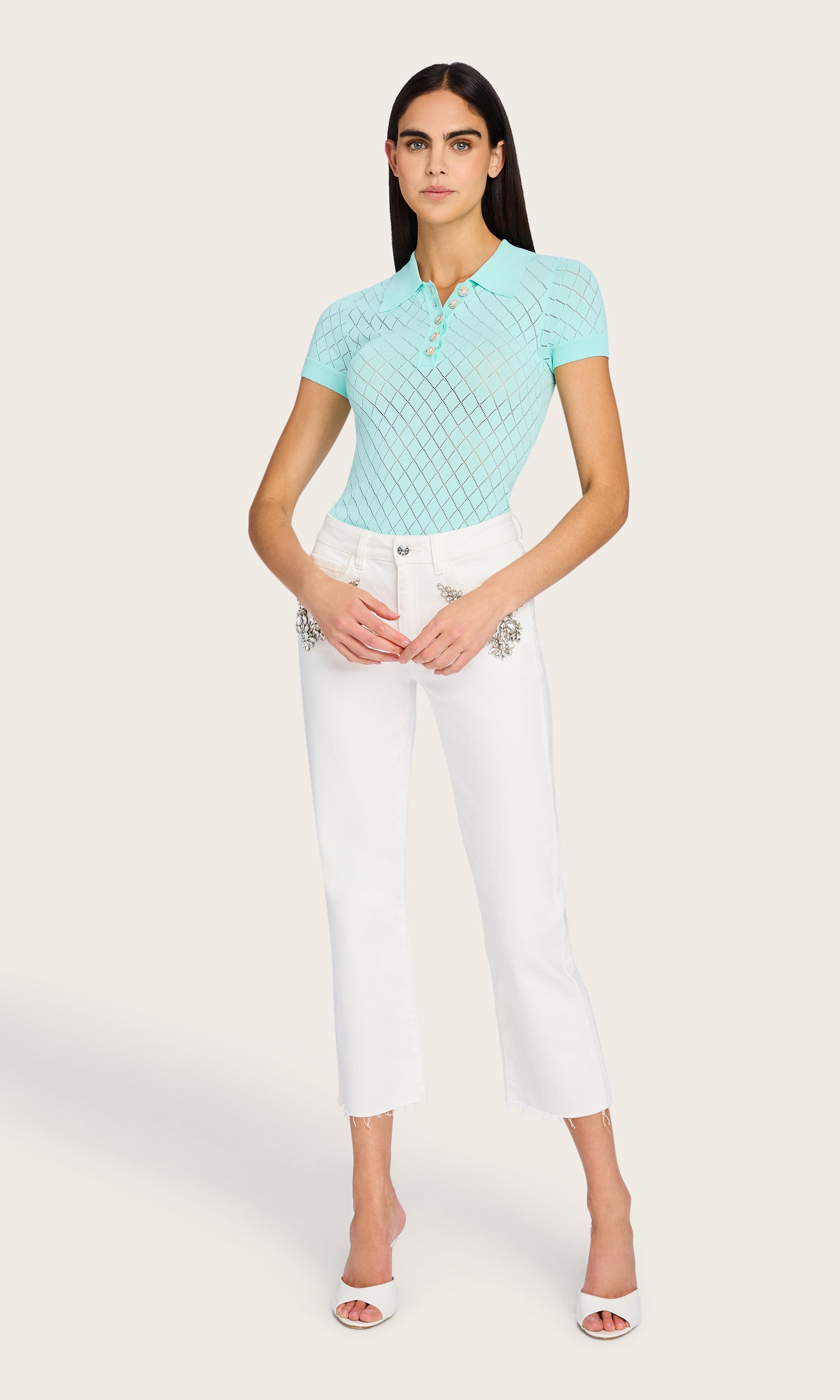 Full-body front view of the model wearing the Calima Sweater in an aqua color, styled with white crystals embellished pants for an effortless summer look.