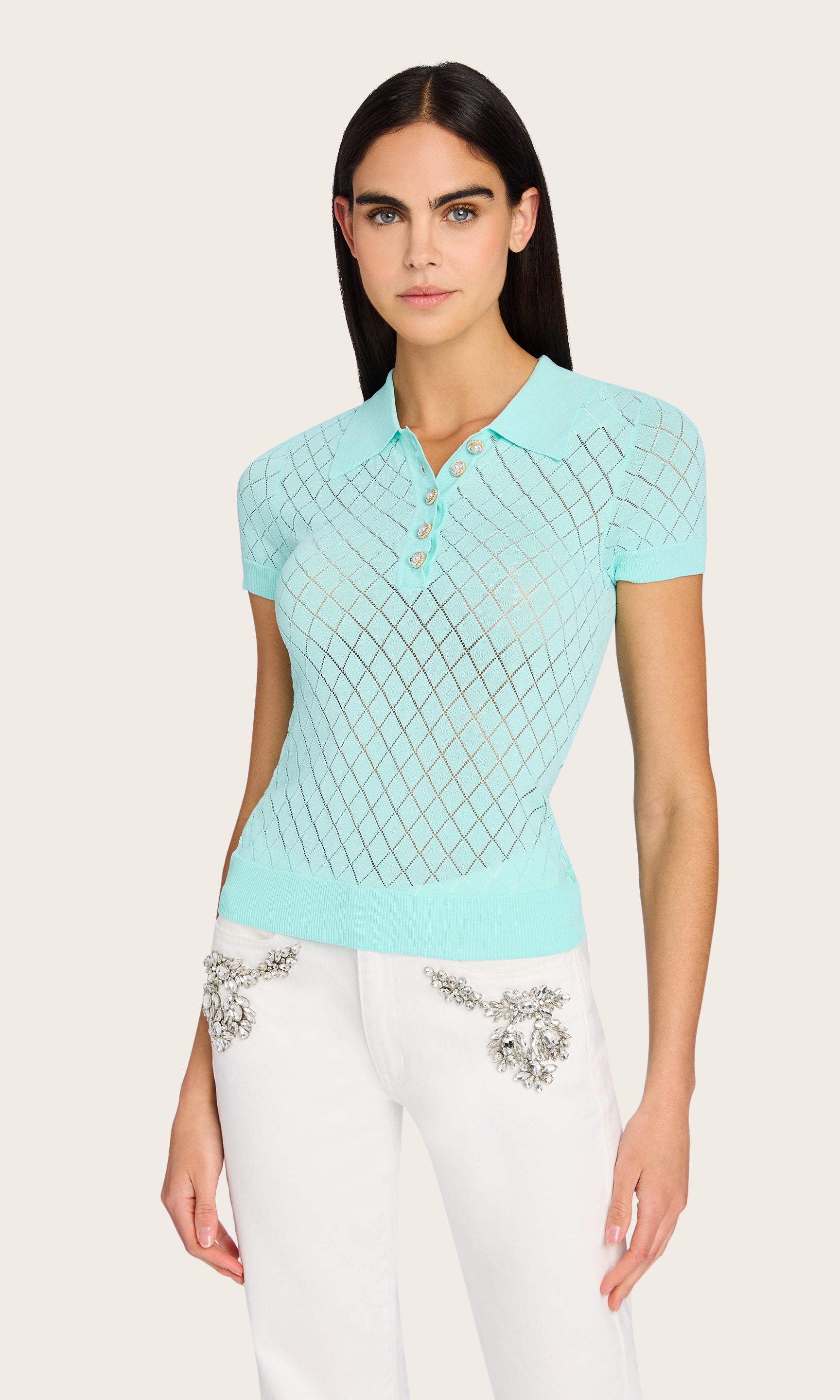 Front view of the model wearing the Calima Sweater in an aqua color, styled with white crystals embellished pants to contrast the mint tone and pointelle texture.