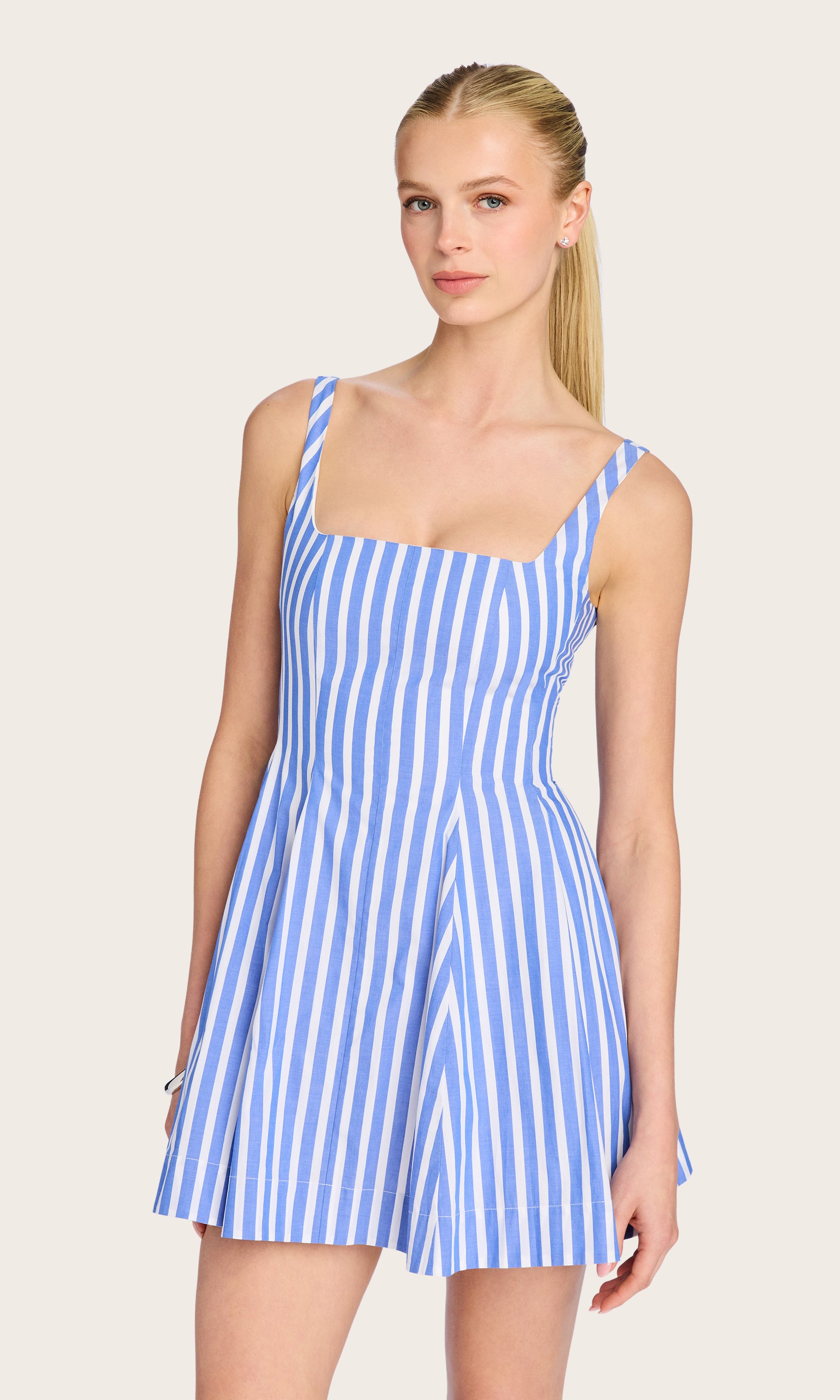 Front view image of model wearing the Courtney mini dress in a white/blue striped pattern with her hair in a ponytail.