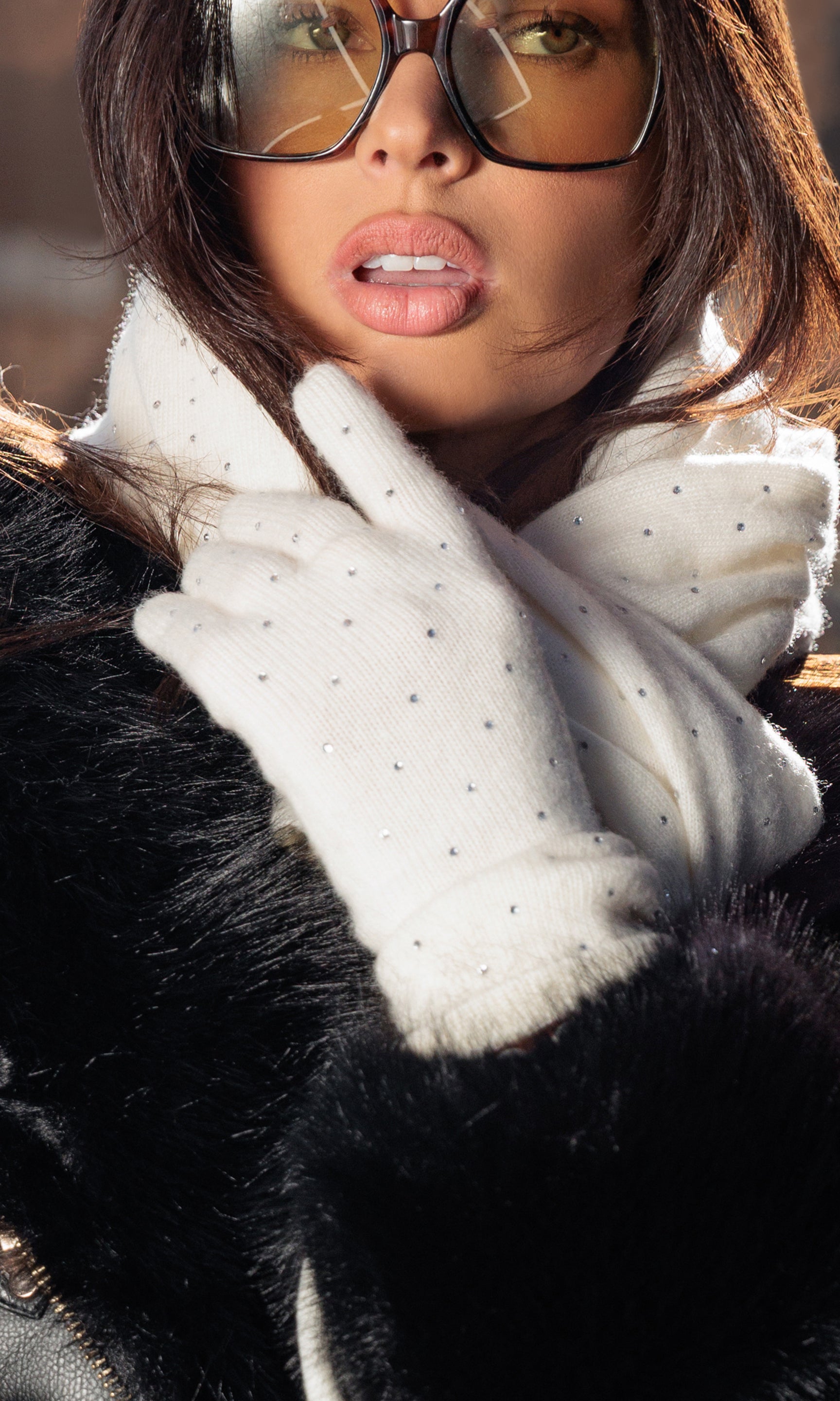 Person wearing a white crystal glove and black fur coat with a blurred background