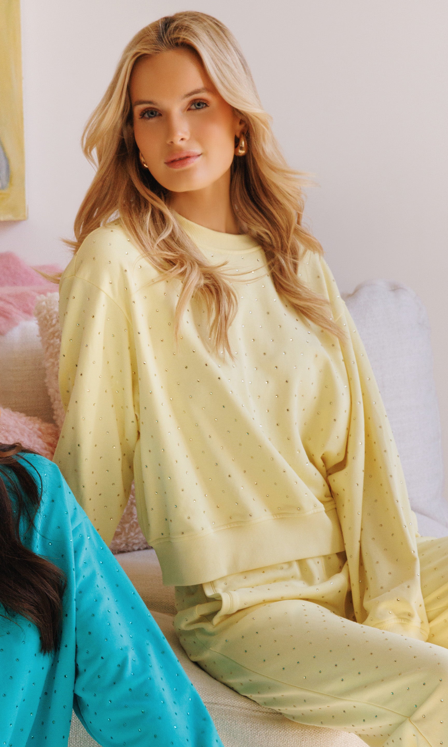 Woman wearing a light yellow crystal outfit sitting on a couch.