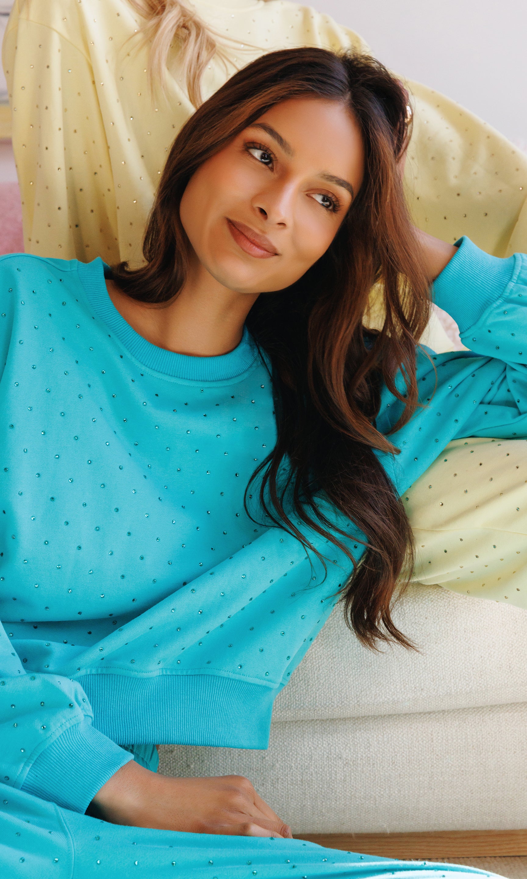Woman wearing a blue polka dot outfit sitting on a couch.