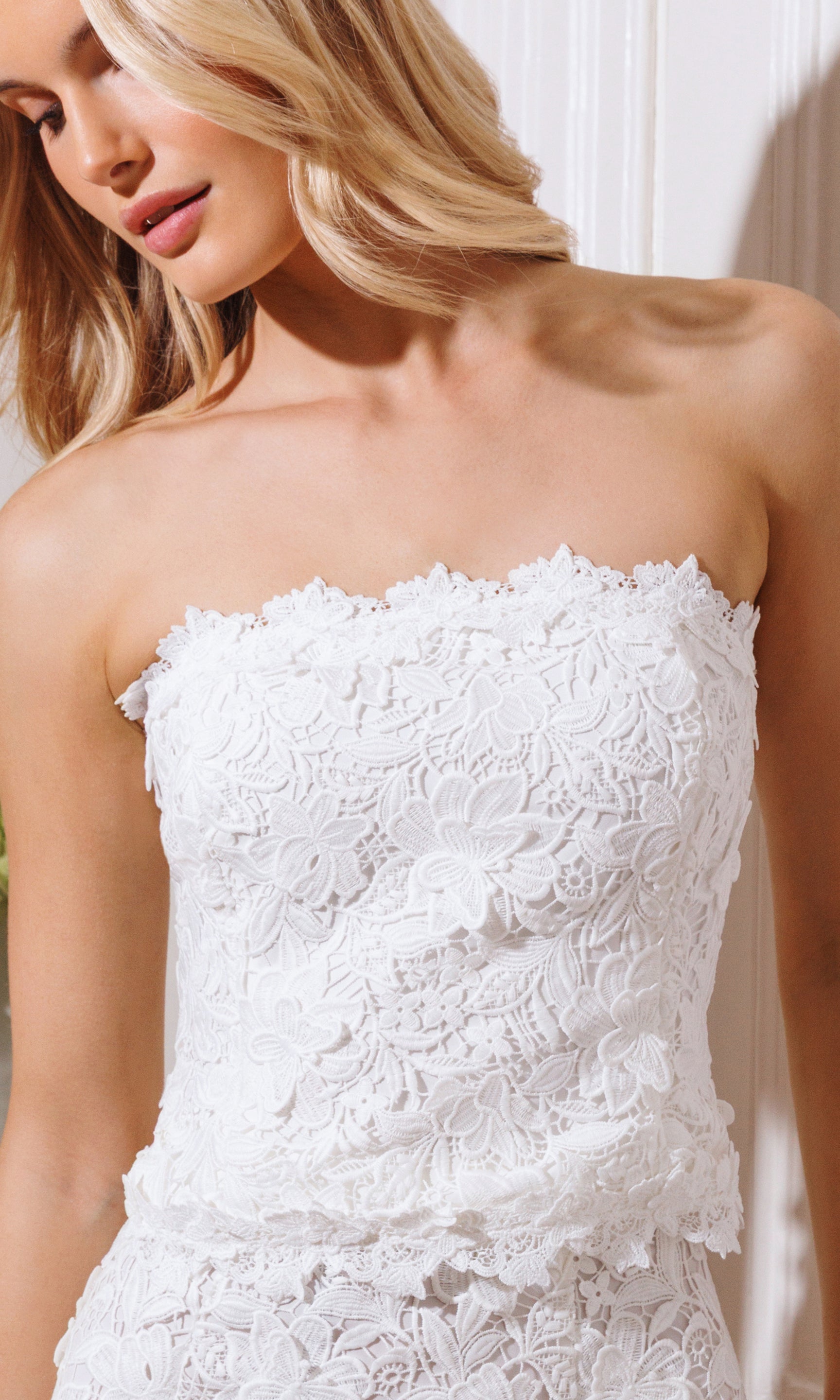 White strapless lace bustier worn by a model with a blurred background