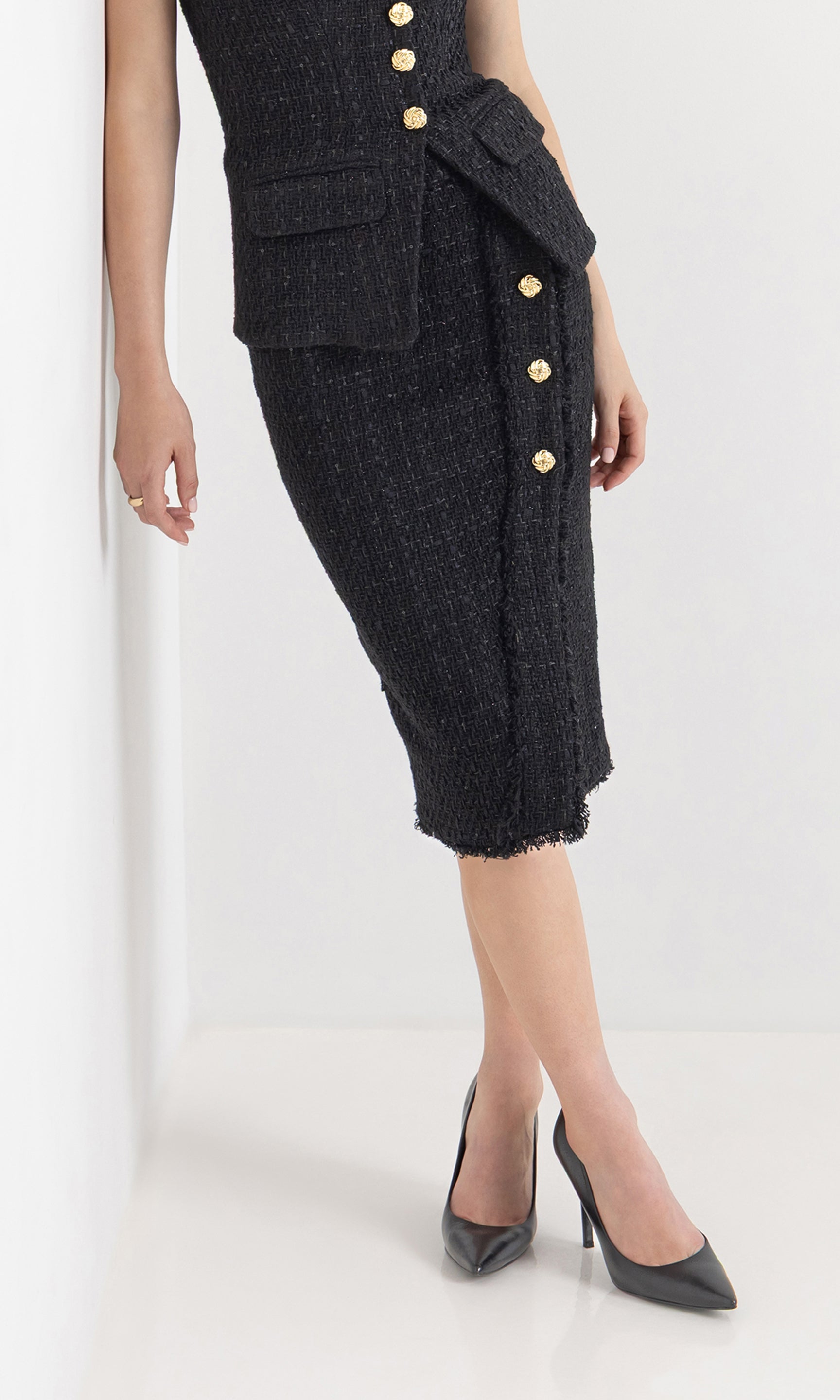 Front view of the model wearing the dio tweed skirt with gold button detailing.