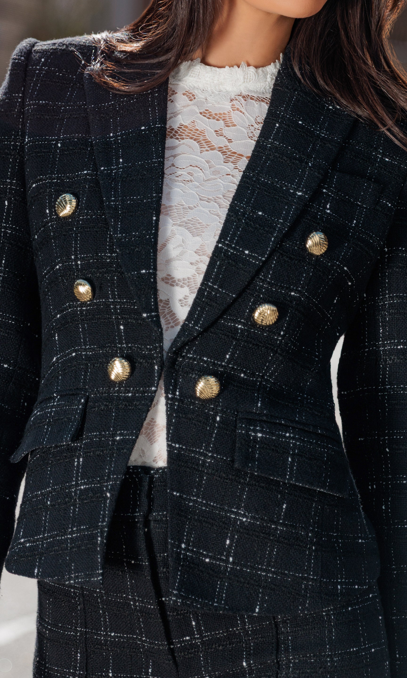 Close-up of black checkered blazer with gold buttons worn by a person