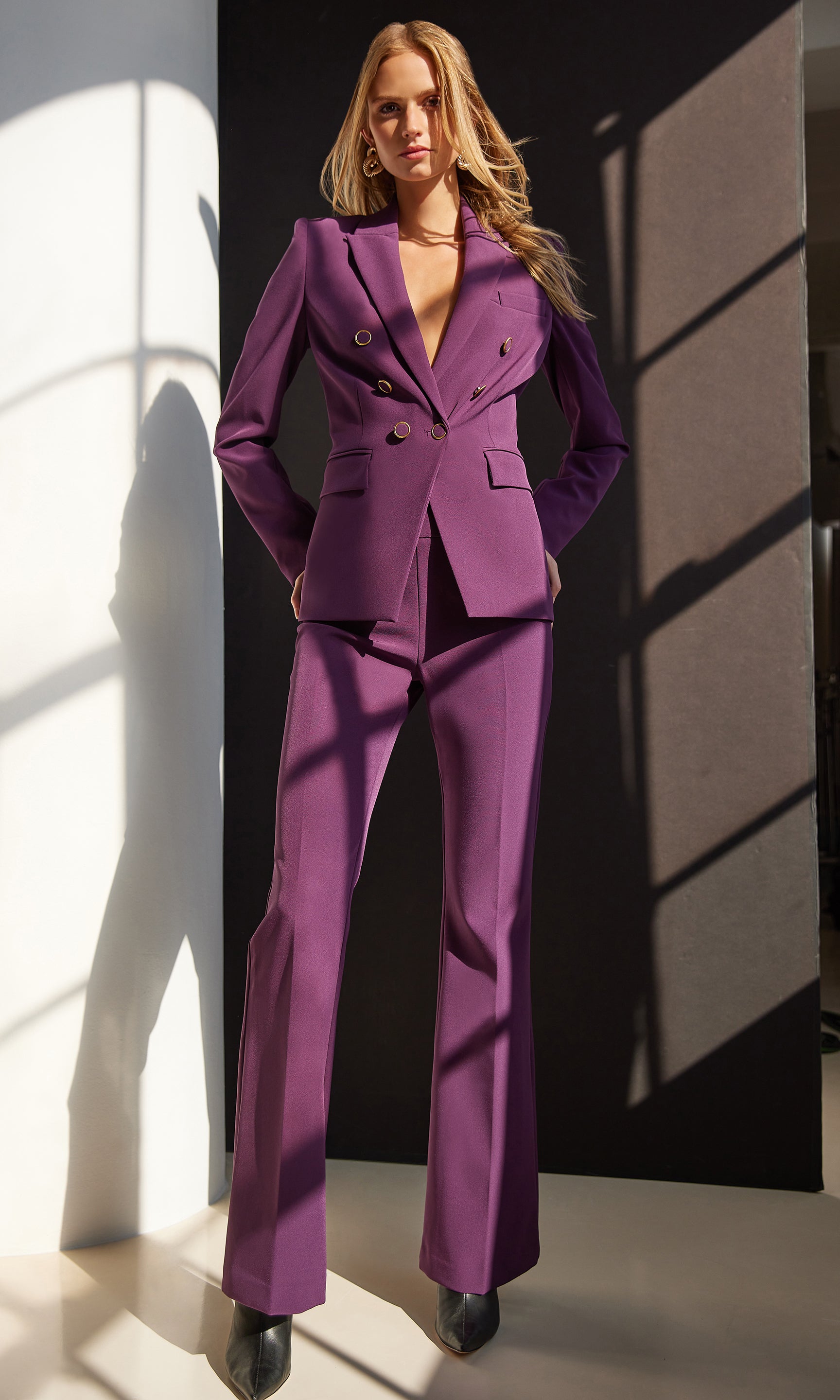 Woman wearing a purple suit standing against a black and white background