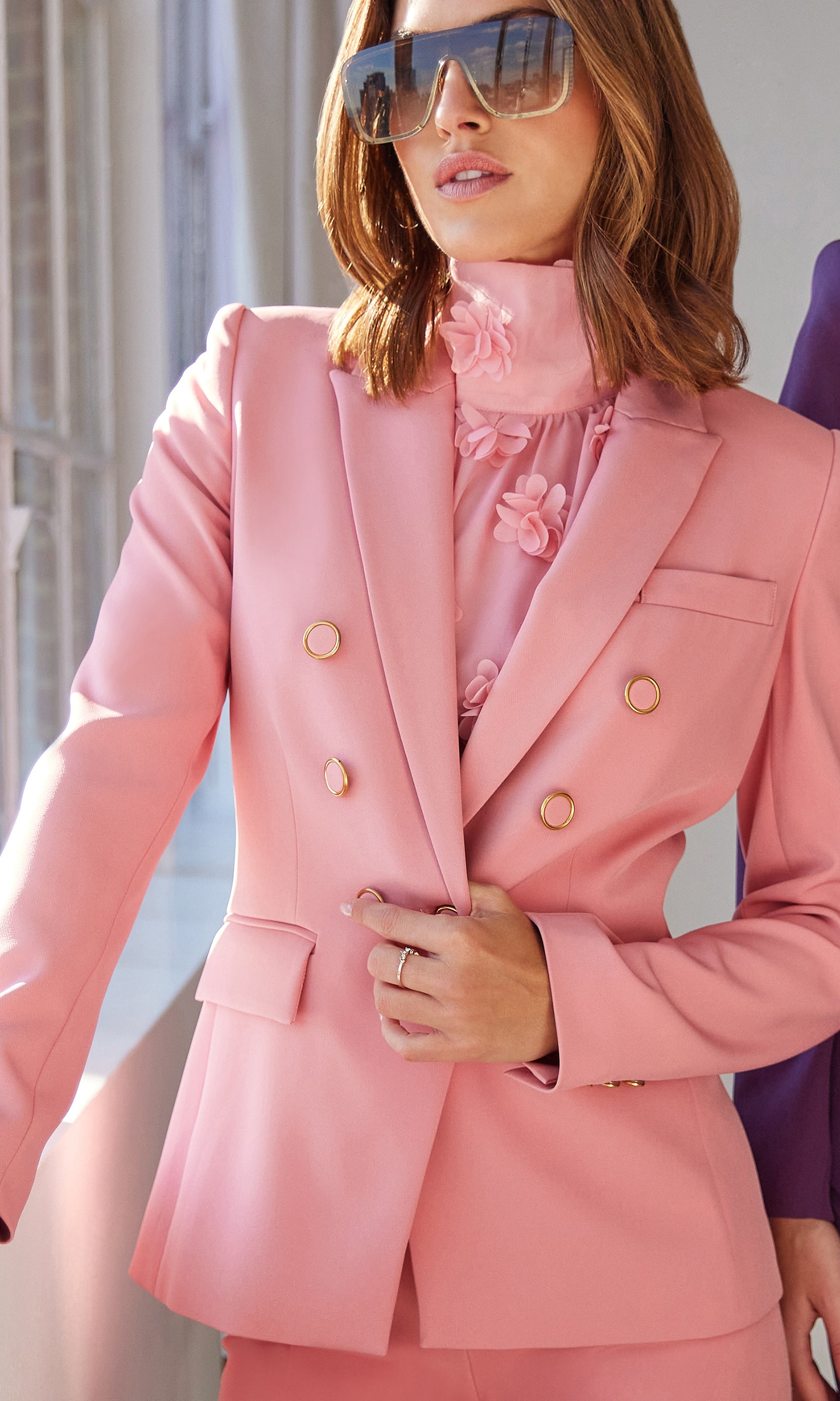 Woman wearing a pink suit with sunglasses outdoors