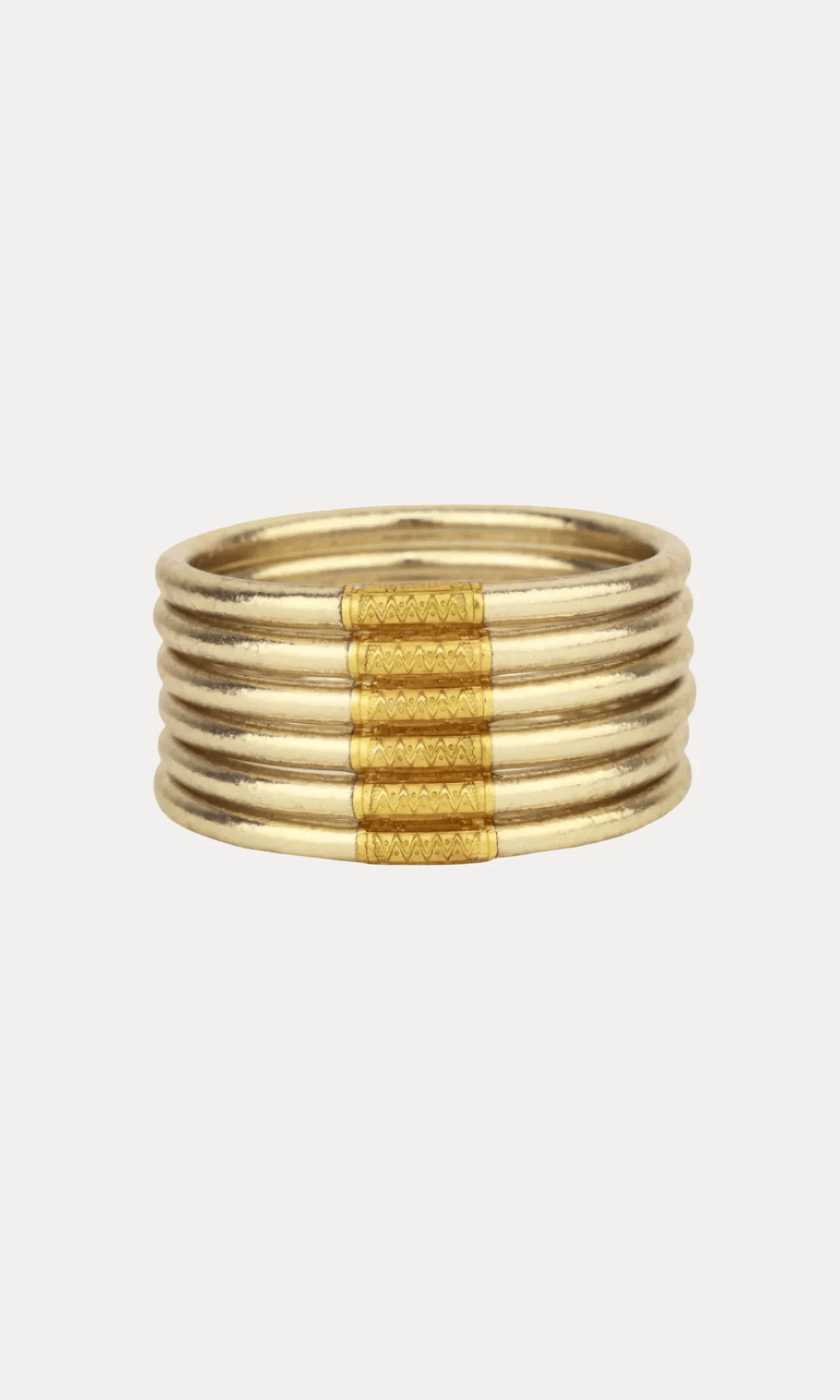 A gold-toned multi-band bracelet with a textured central band, shown against a plain light gray background.