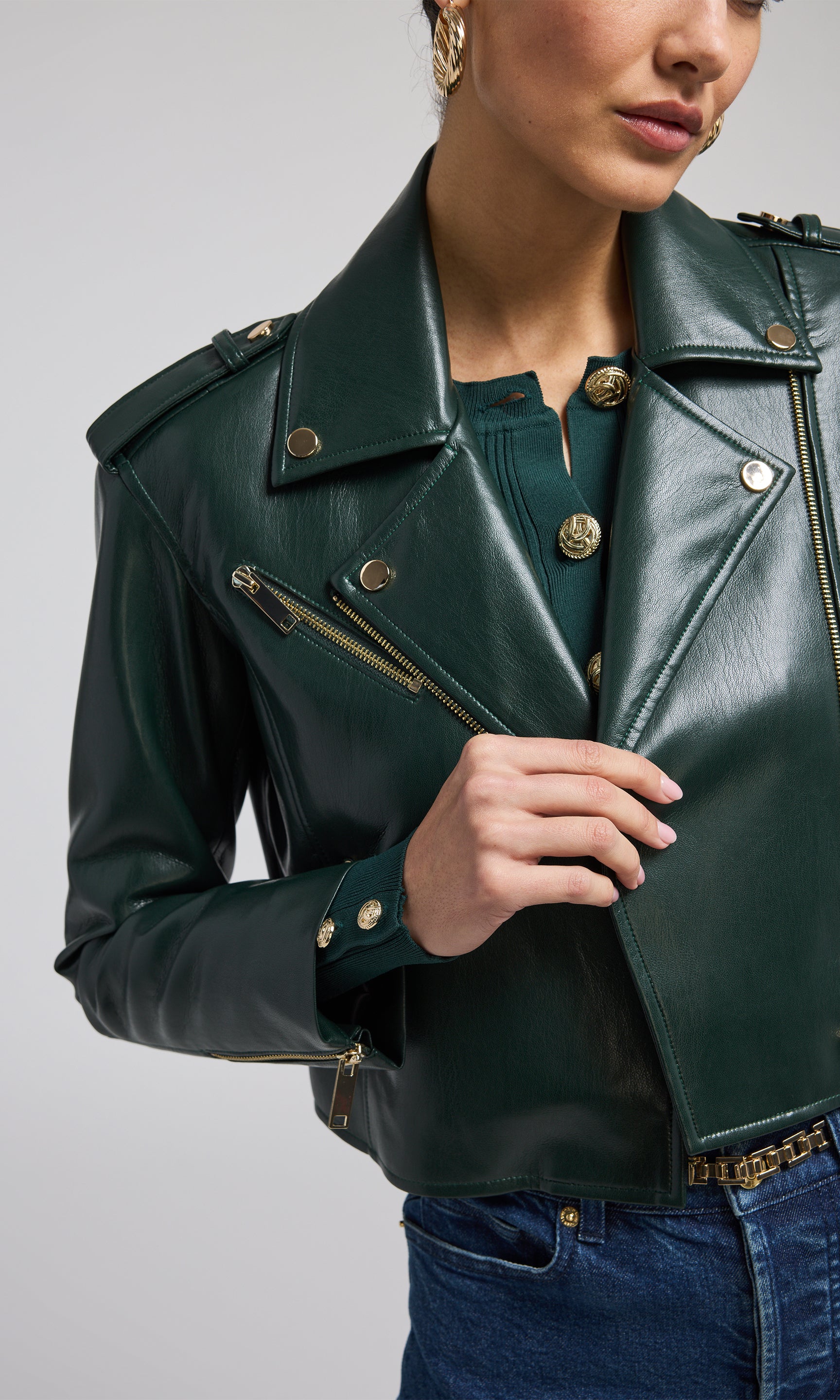 A fashionable green leather jacket adorned with gold zippers, highlighting its contemporary appeal.