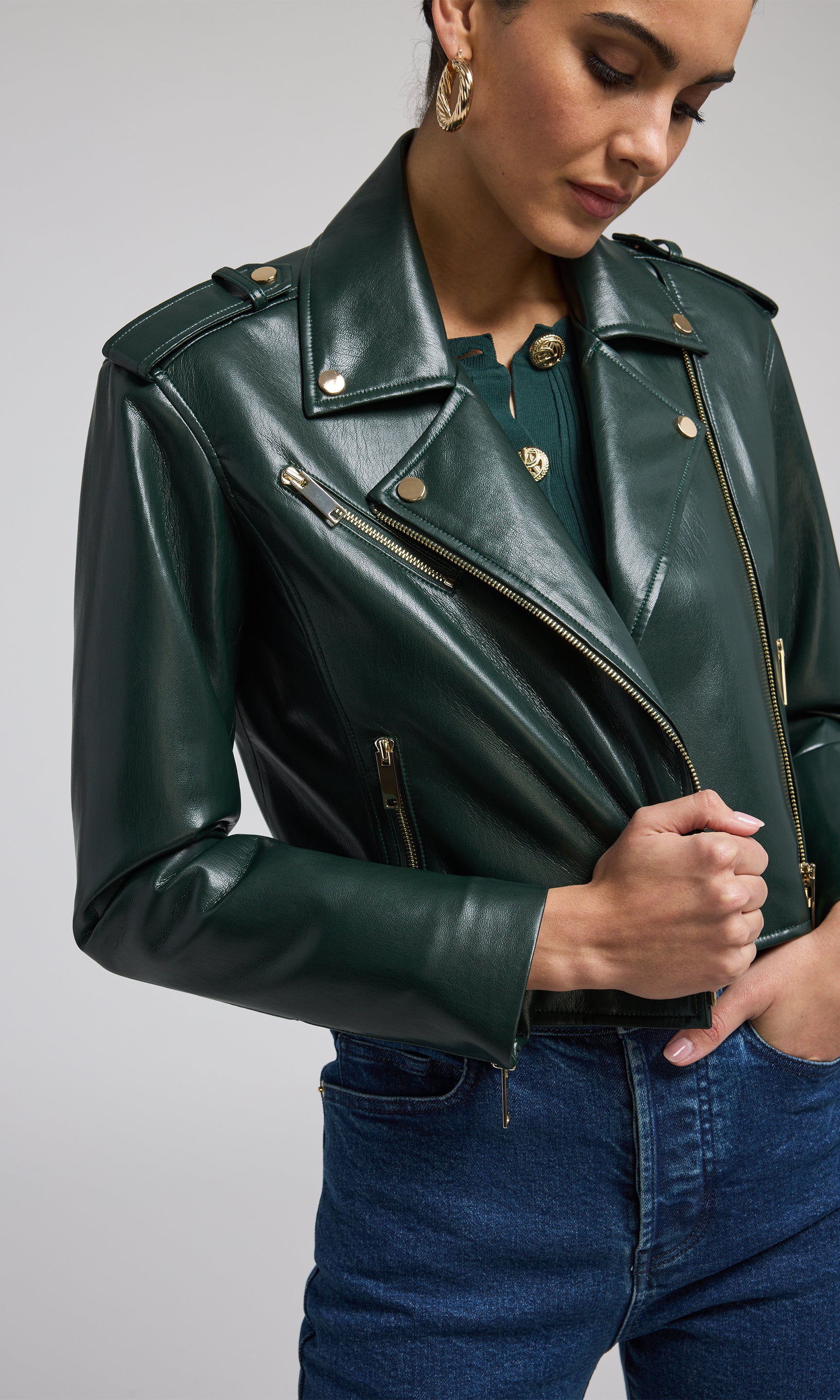 A fashionable green leather jacket adorned with gold zippers, highlighting its contemporary appeal.