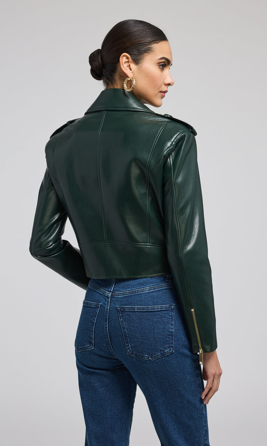 A fashionable green leather jacket adorned with gold zippers, highlighting its contemporary appeal.