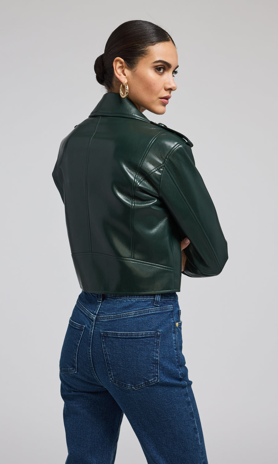 A fashionable green leather jacket adorned with gold zippers, highlighting its contemporary appeal.