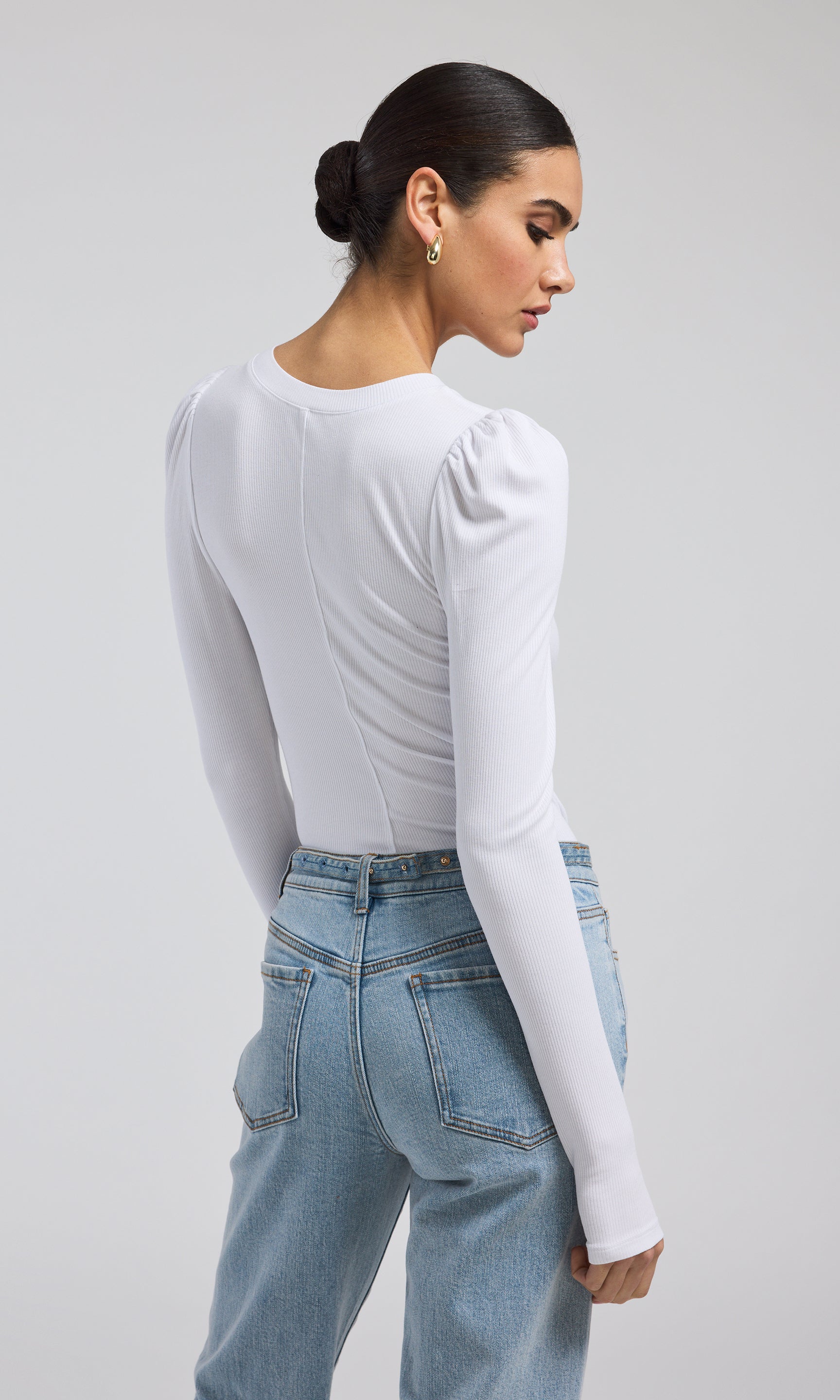 The white ribbed top is adorned with buttons on the sleeves, adding a unique touch to its elegant appearance