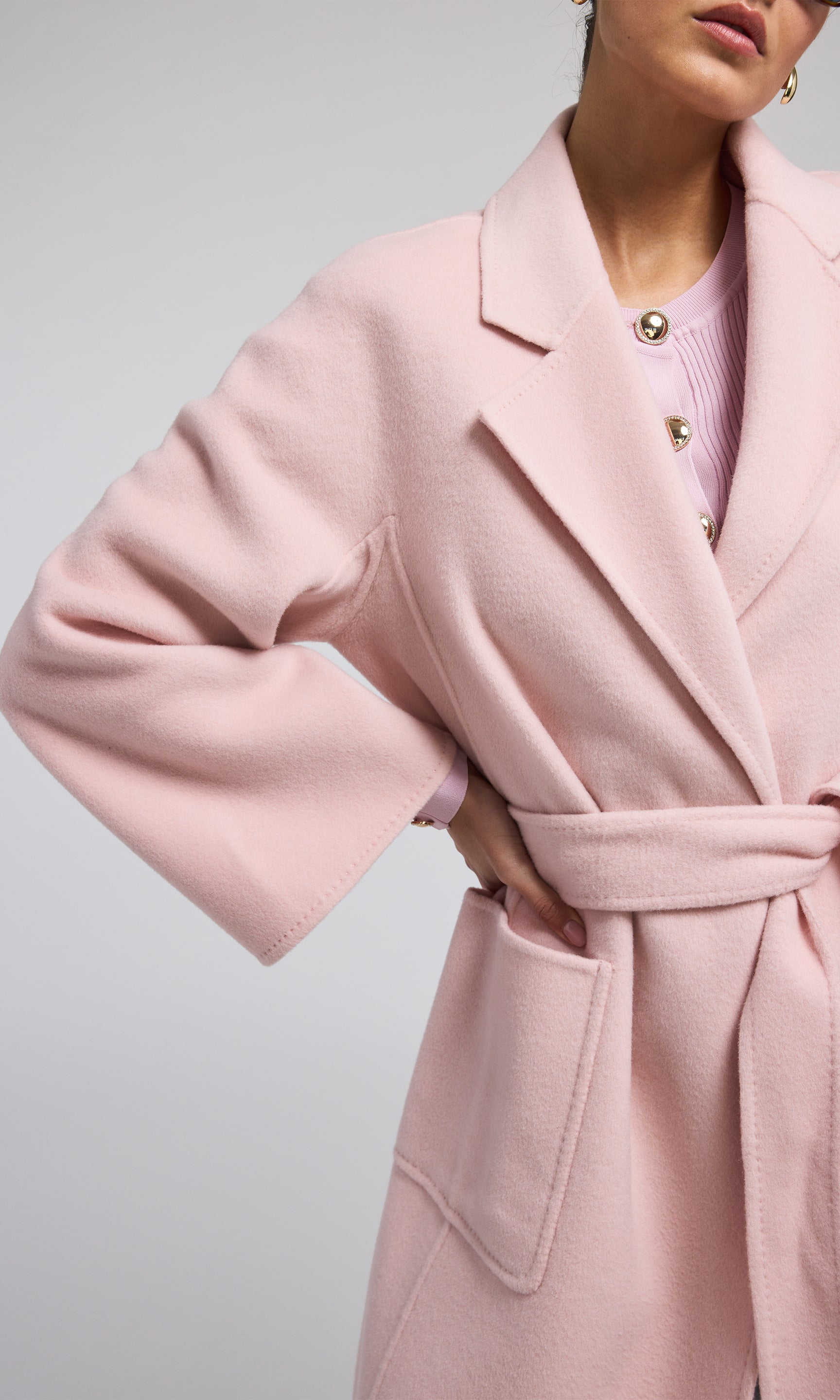 A pink wool coat featuring a stylish belt, showcasing a warm and fashionable design suitable for various occasions.