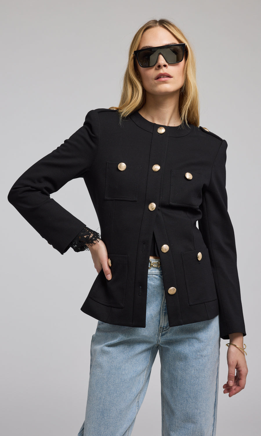 A chic black blazer with buttons is worn by the model, highlighting a refined and fashionable appearance. 