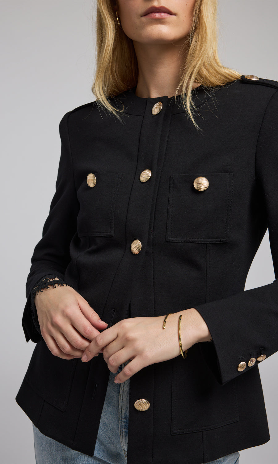 A chic black blazer with buttons is worn by the model, highlighting a refined and fashionable appearance. 